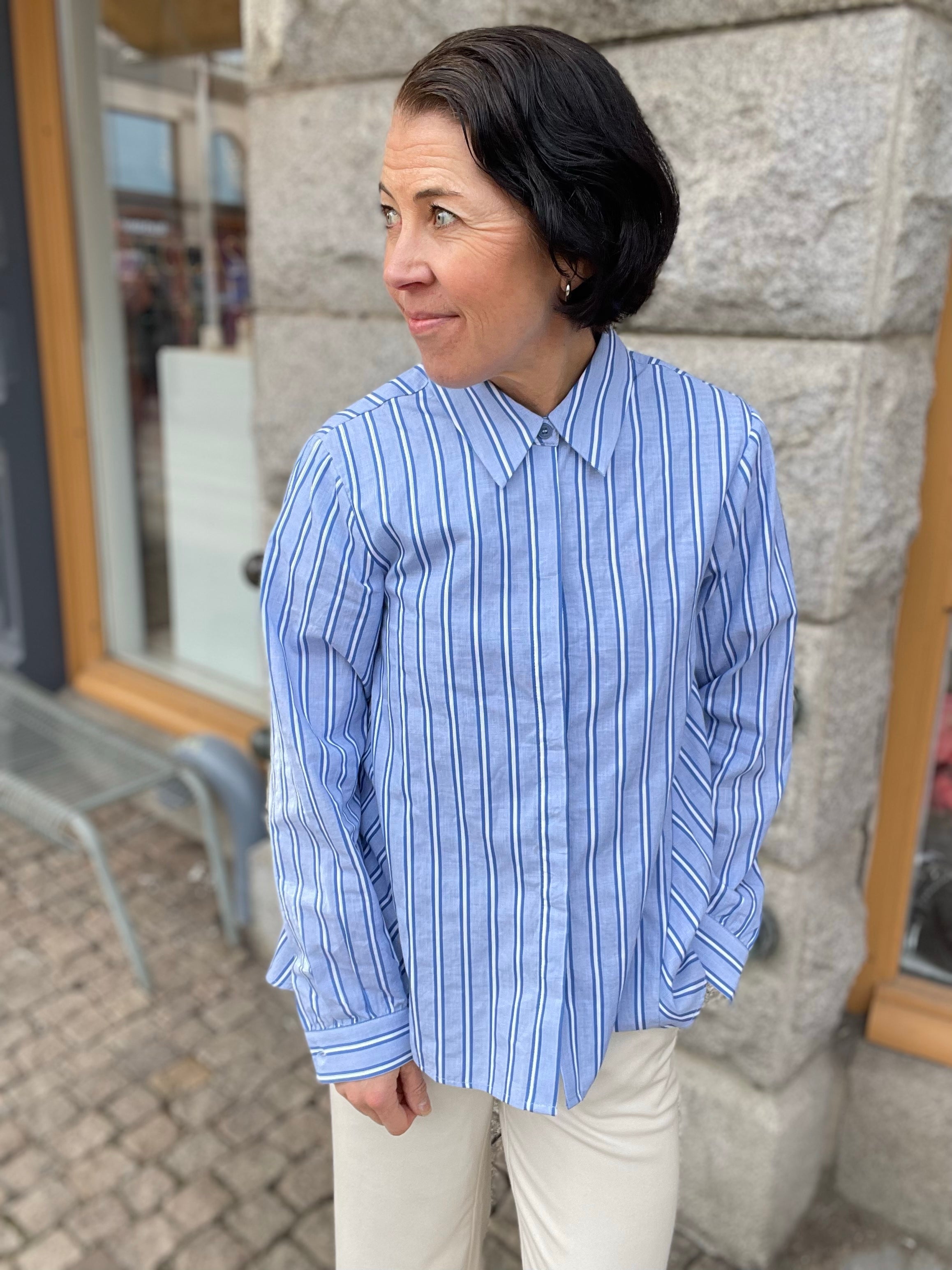 Blå vit randig skjorta med krage och dold knäppning.