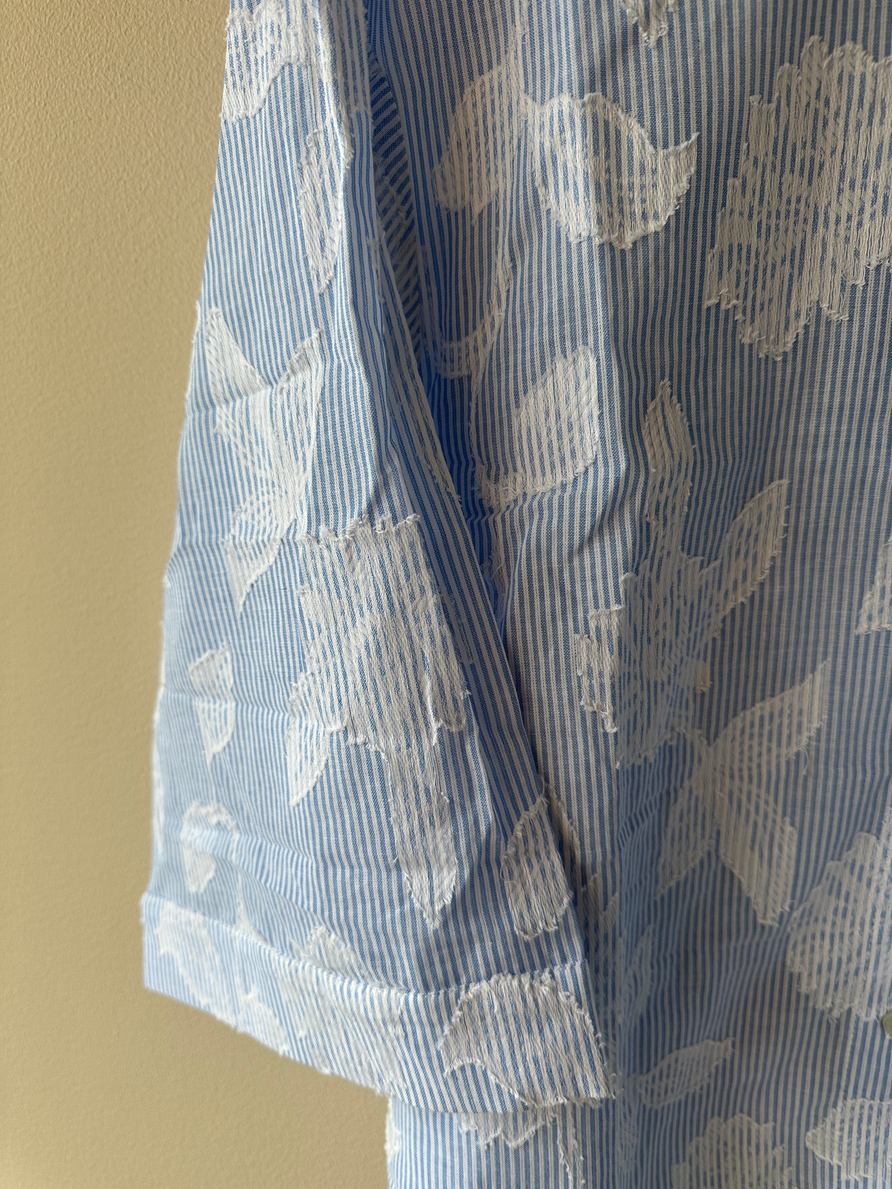 Svagt blå vit randig skjorta med brodyr detaljer av vita blad.