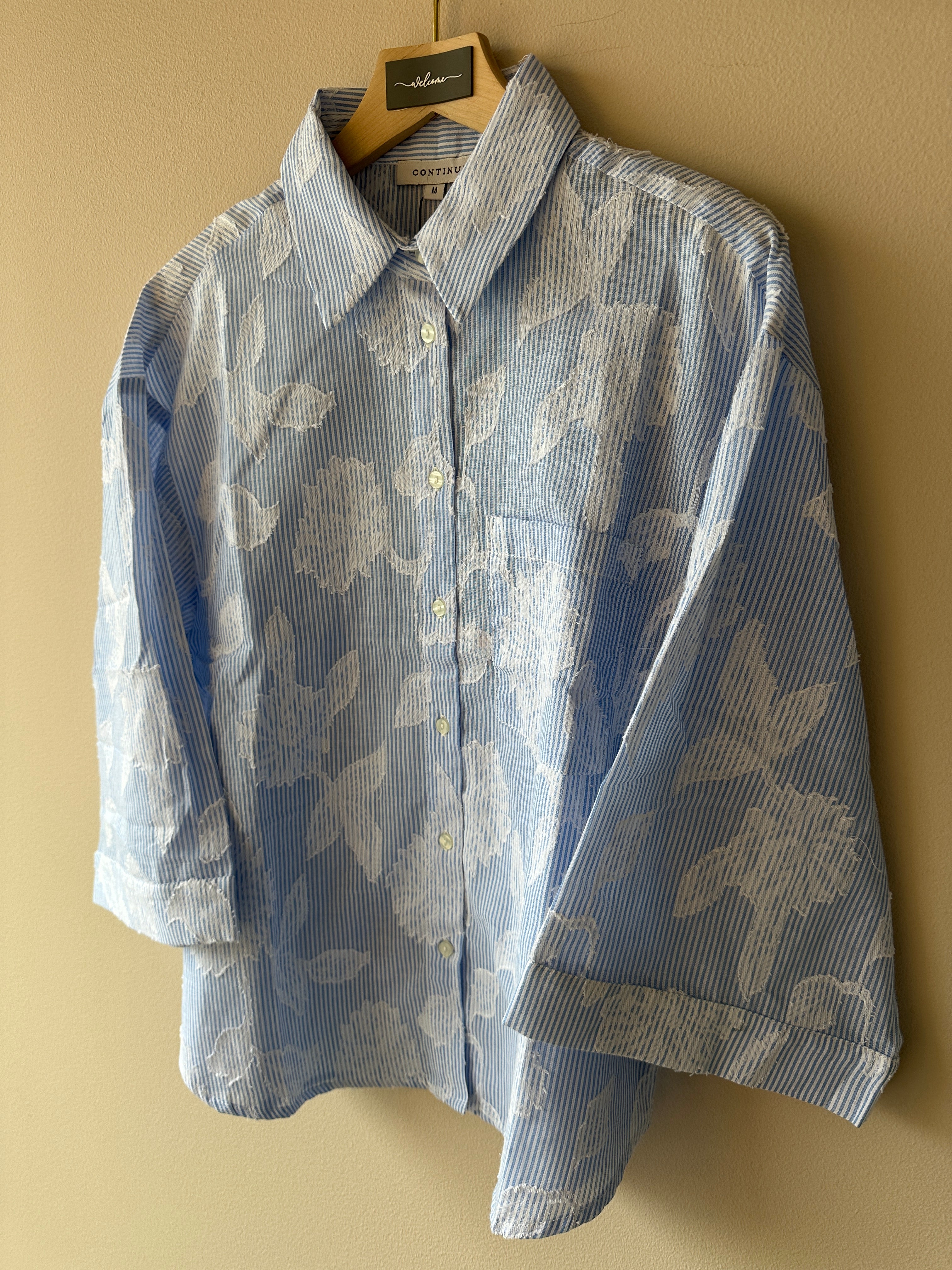 Svagt blå vit randig skjorta med brodyr detaljer av vita blad.