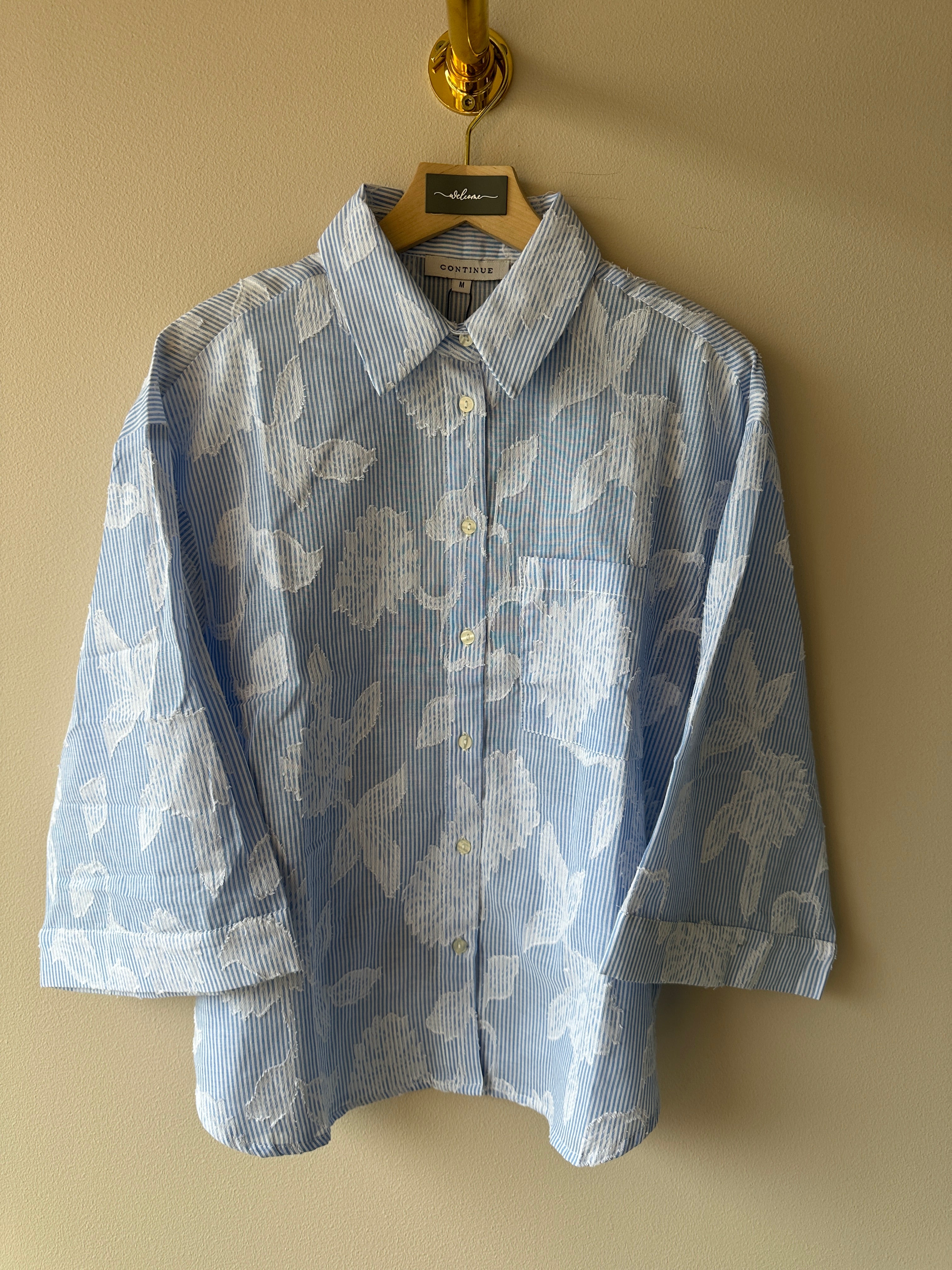 Svagt blå vit randig skjorta med brodyr detaljer av vita blad.