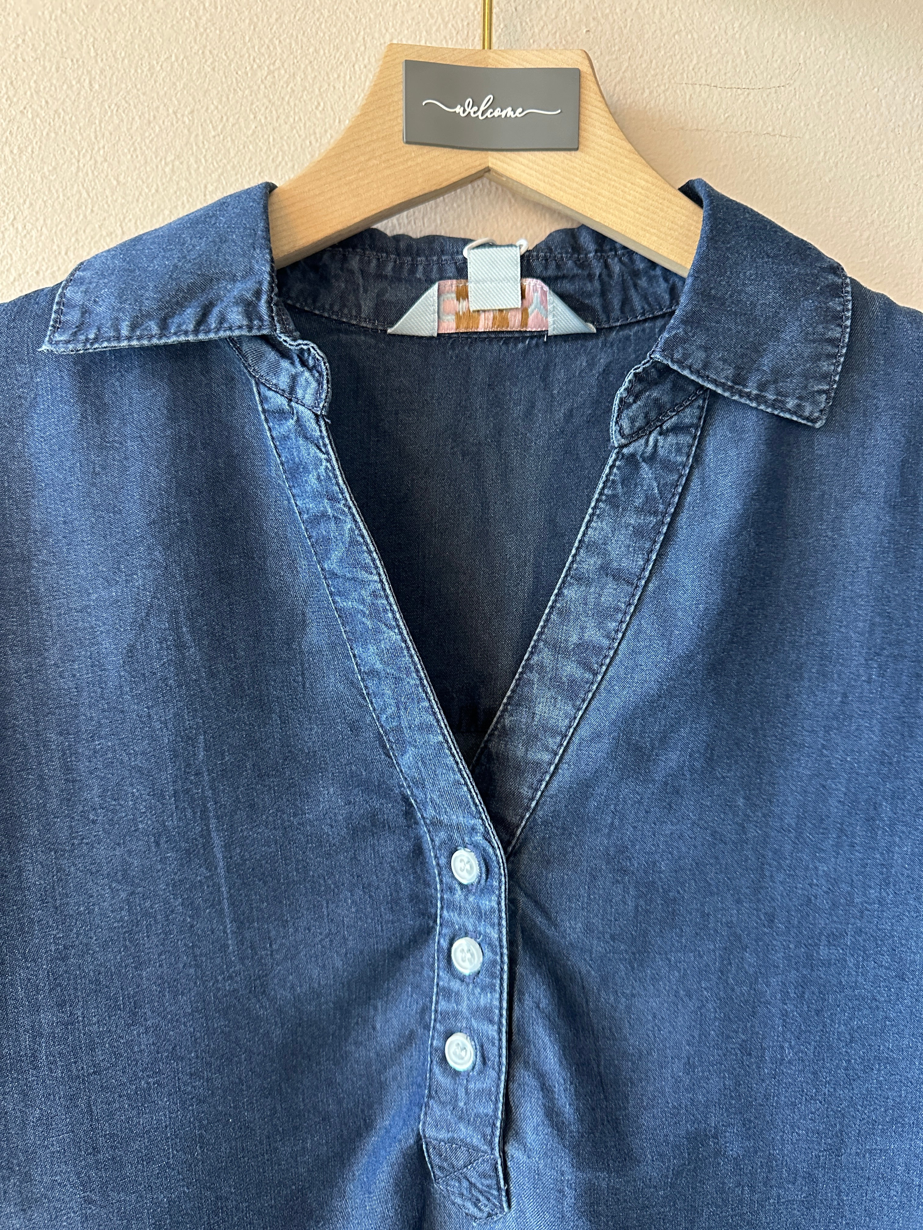 Blå jeans piké med kort ärm och tre knappar i v-ringningen.