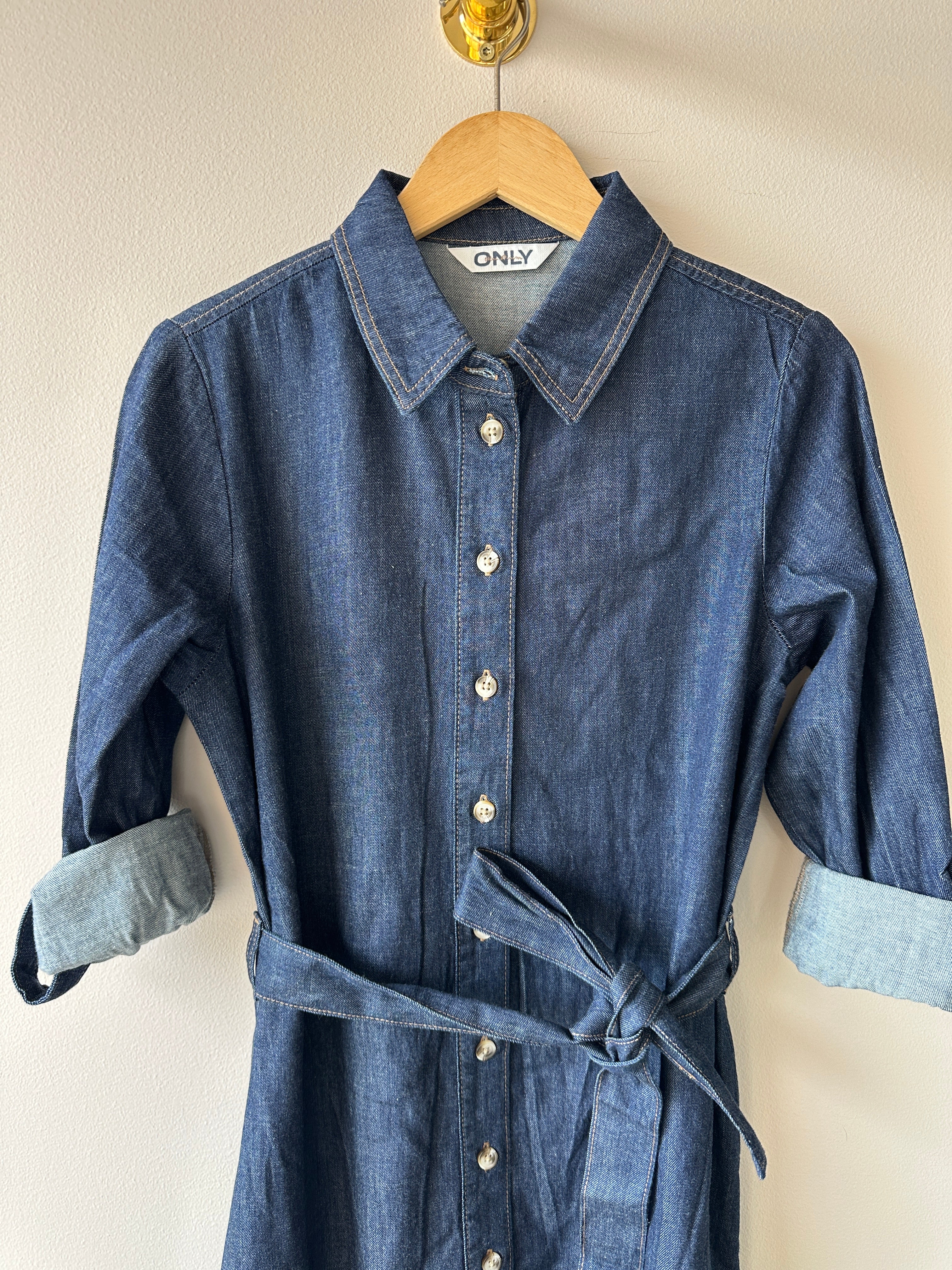 Skjortklänning i jeansmaterial med knäppning framtill med ett skärp. Volang nertill.