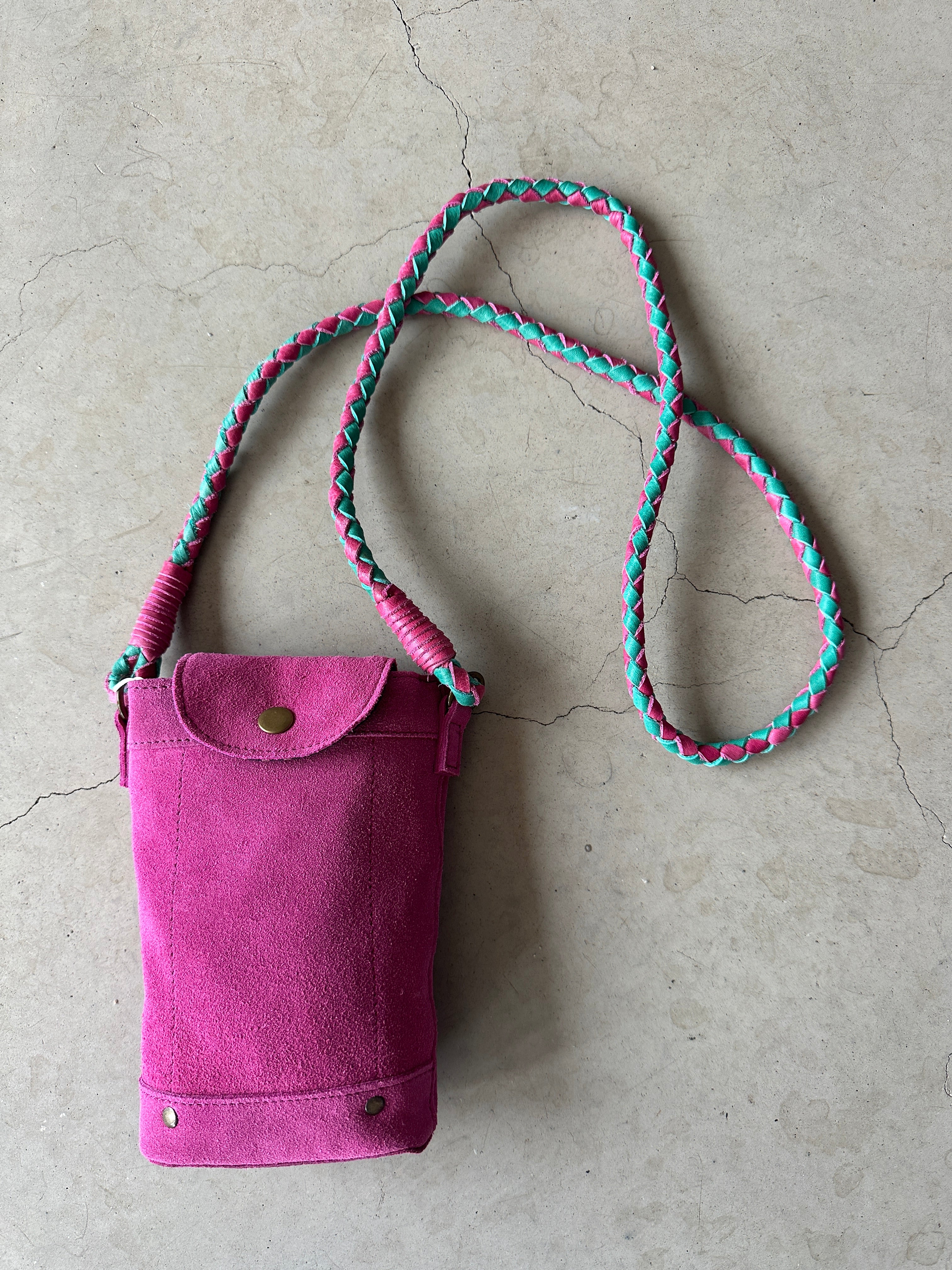 Liten mobilväska i fuchsia mocka med flätat axelband i cerise och mintgrönt, tryckknapplås och liten ytterficka.