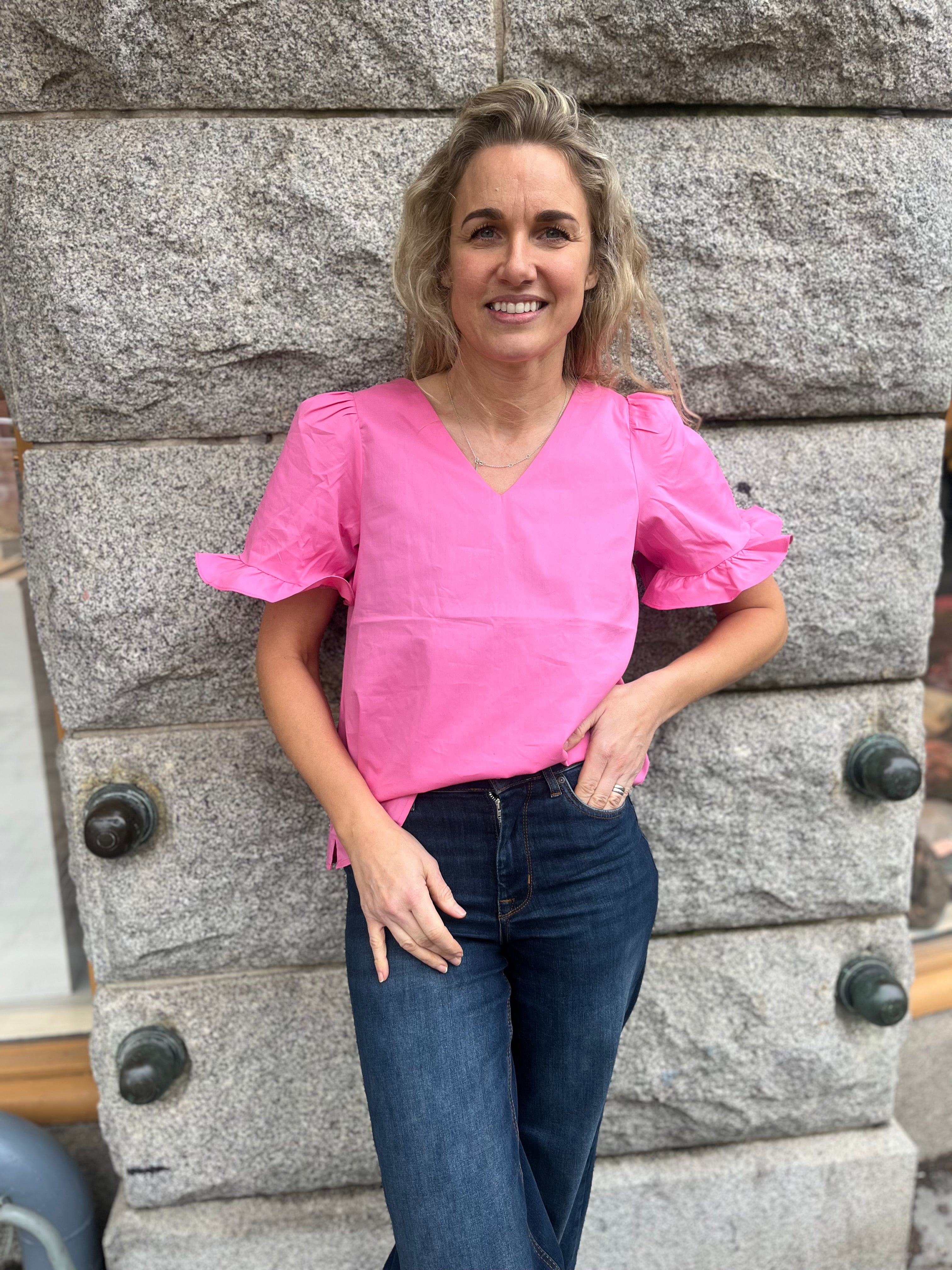 Rosa blus med volanger och v-ringning.