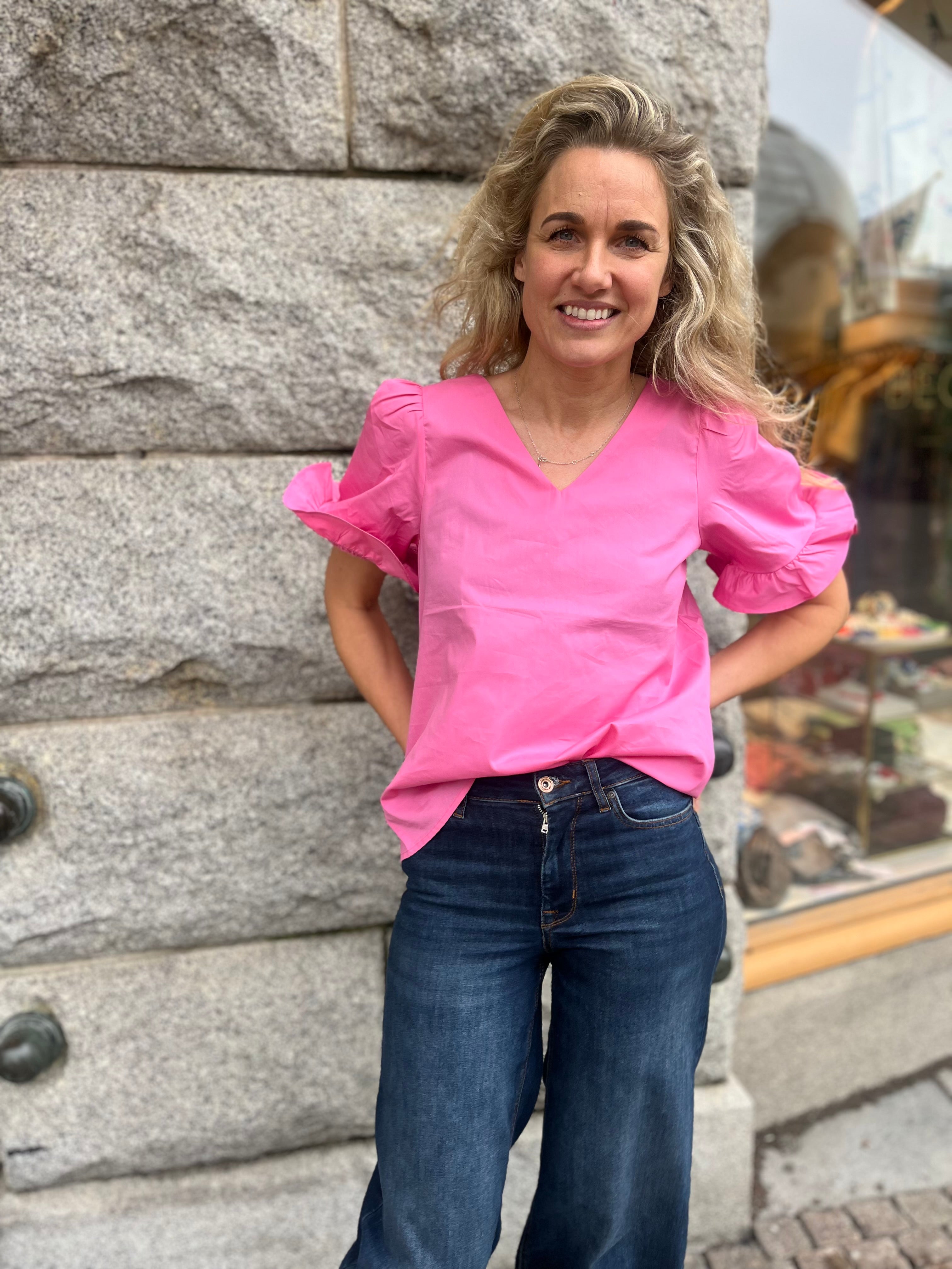 Rosa blus med volanger och v-ringning.