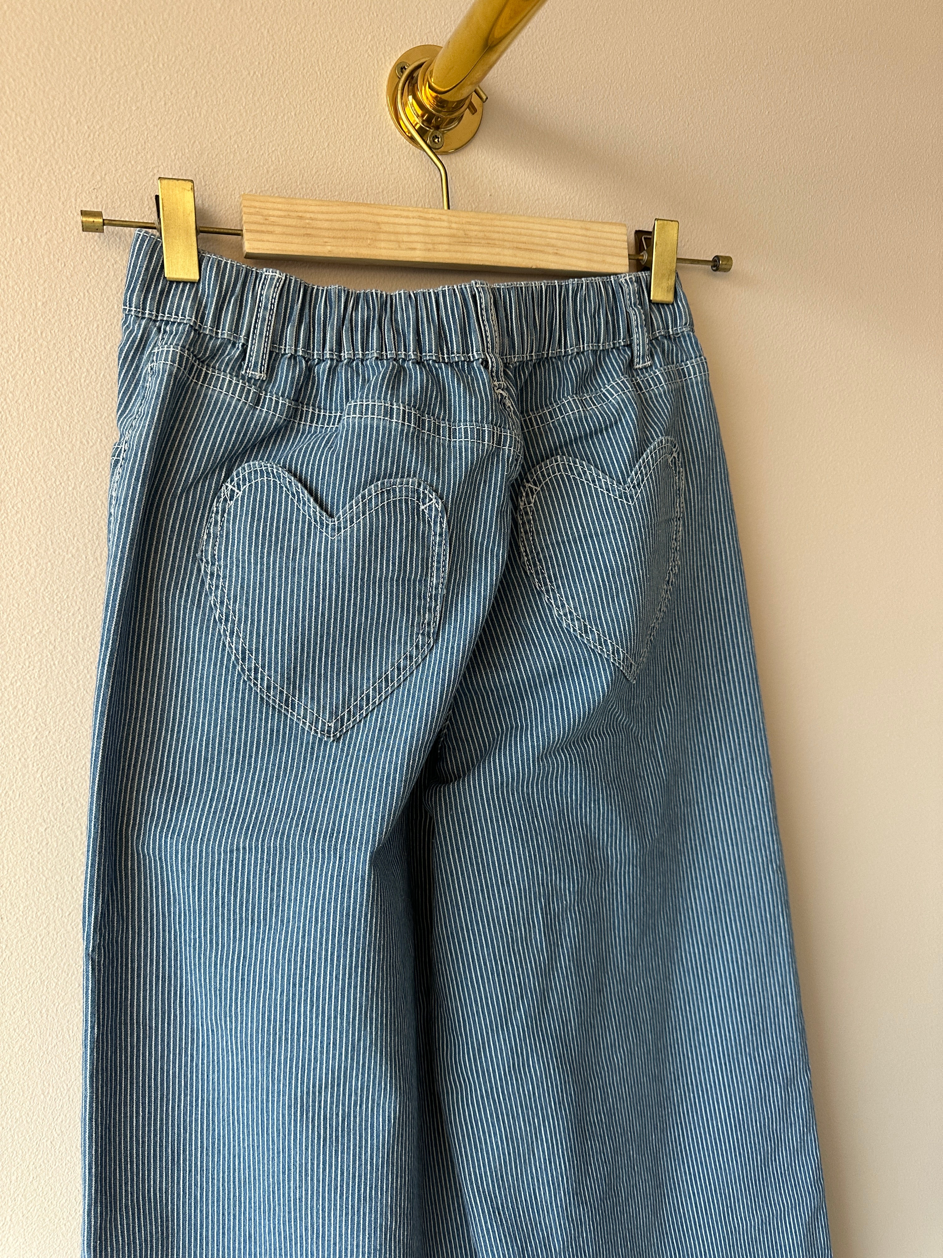 Bakfickor formade som hjärtan på blåvitrandig jeans, hängda på galge.