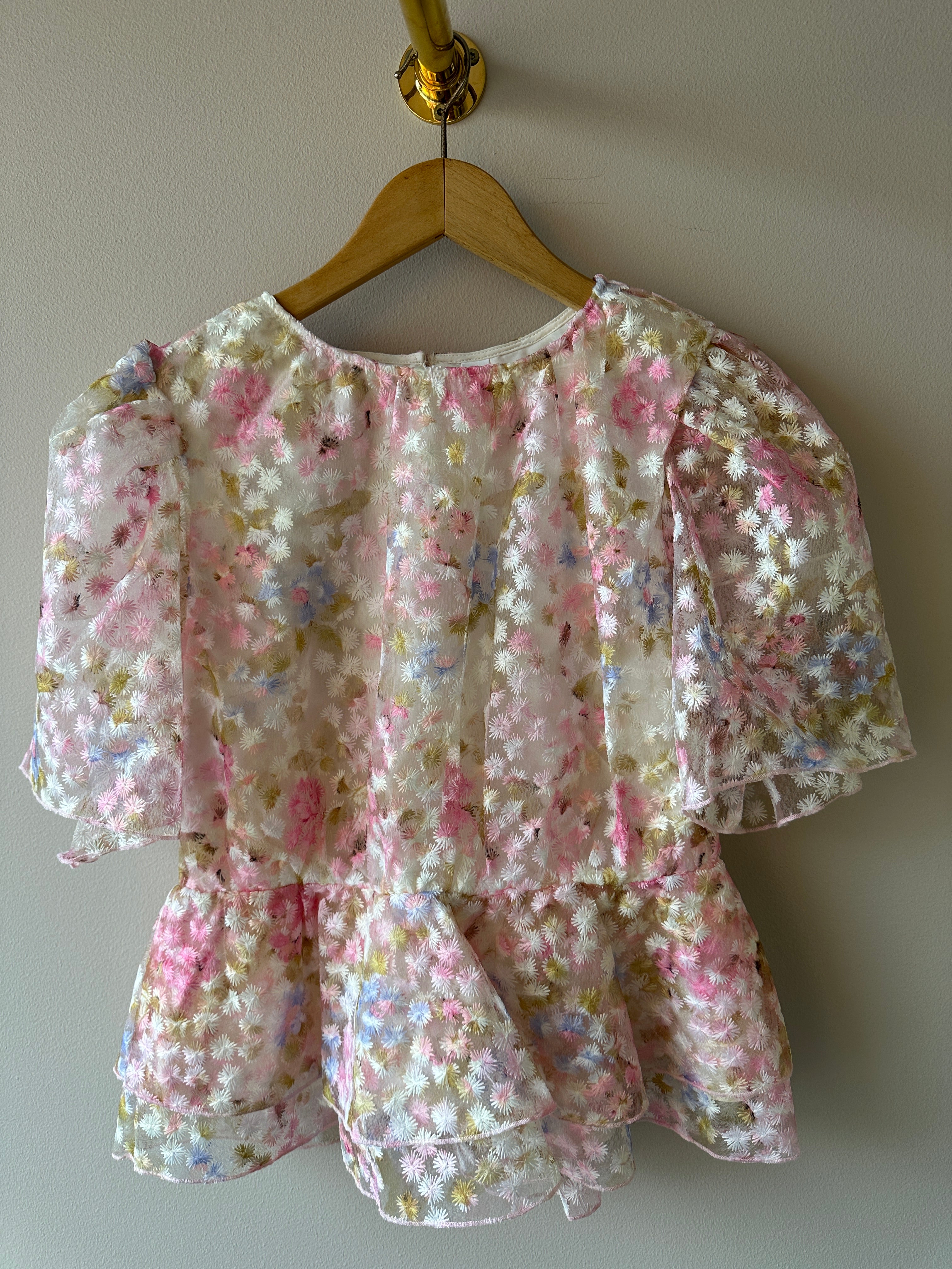 Yasleanna Short Sleeve Top New Show Pristine Leanna. Blus med en vit grund och rosa, blå och gröna blommor. Med puffärm men en liten utsvällning vid midjan.