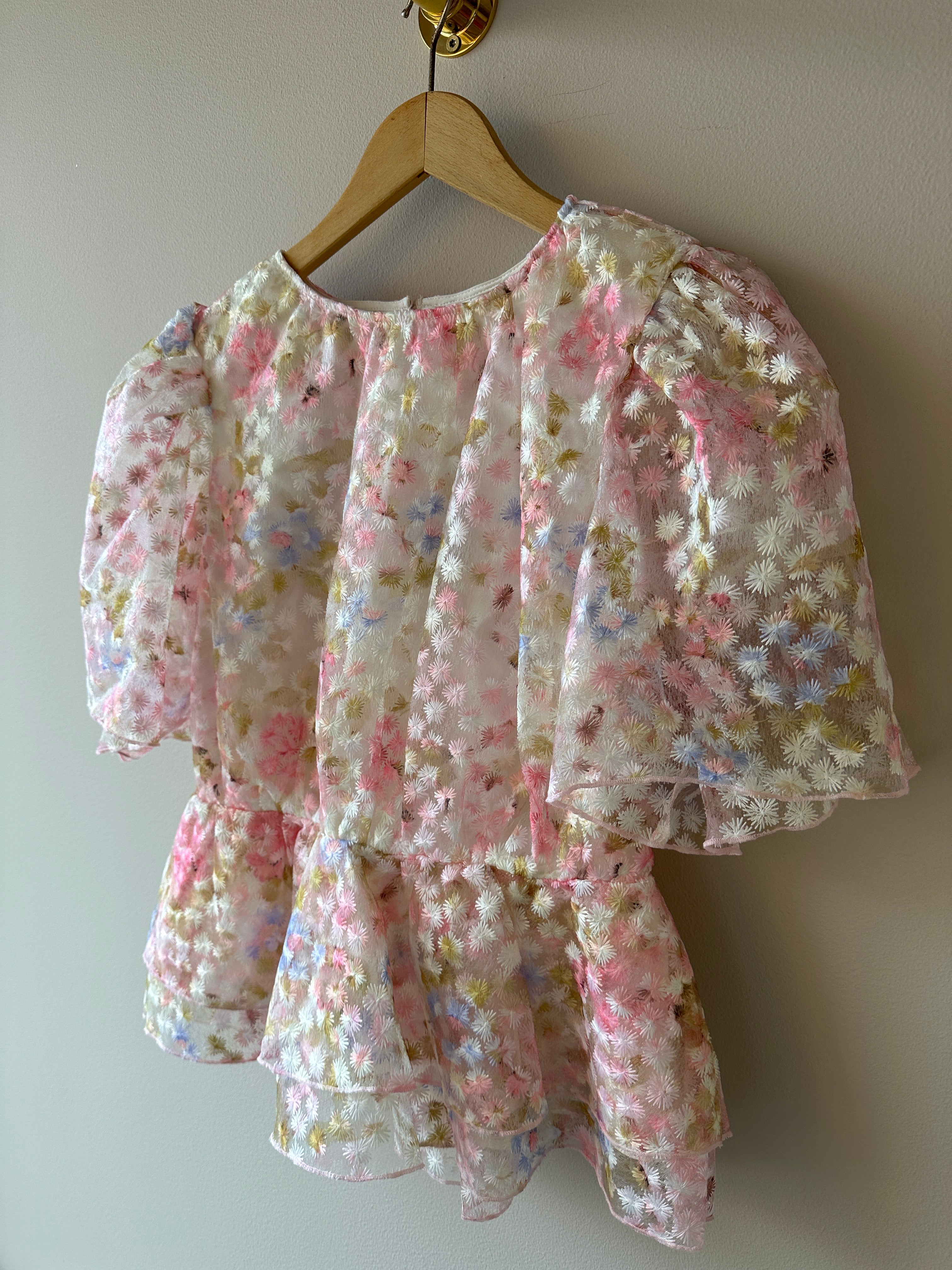 Yasleanna Short Sleeve Top New Show Pristine Leanna. Blus med en vit grund och rosa, blåa och gröna blommor. Med puffärm men en liten utsvällning vid midjan.