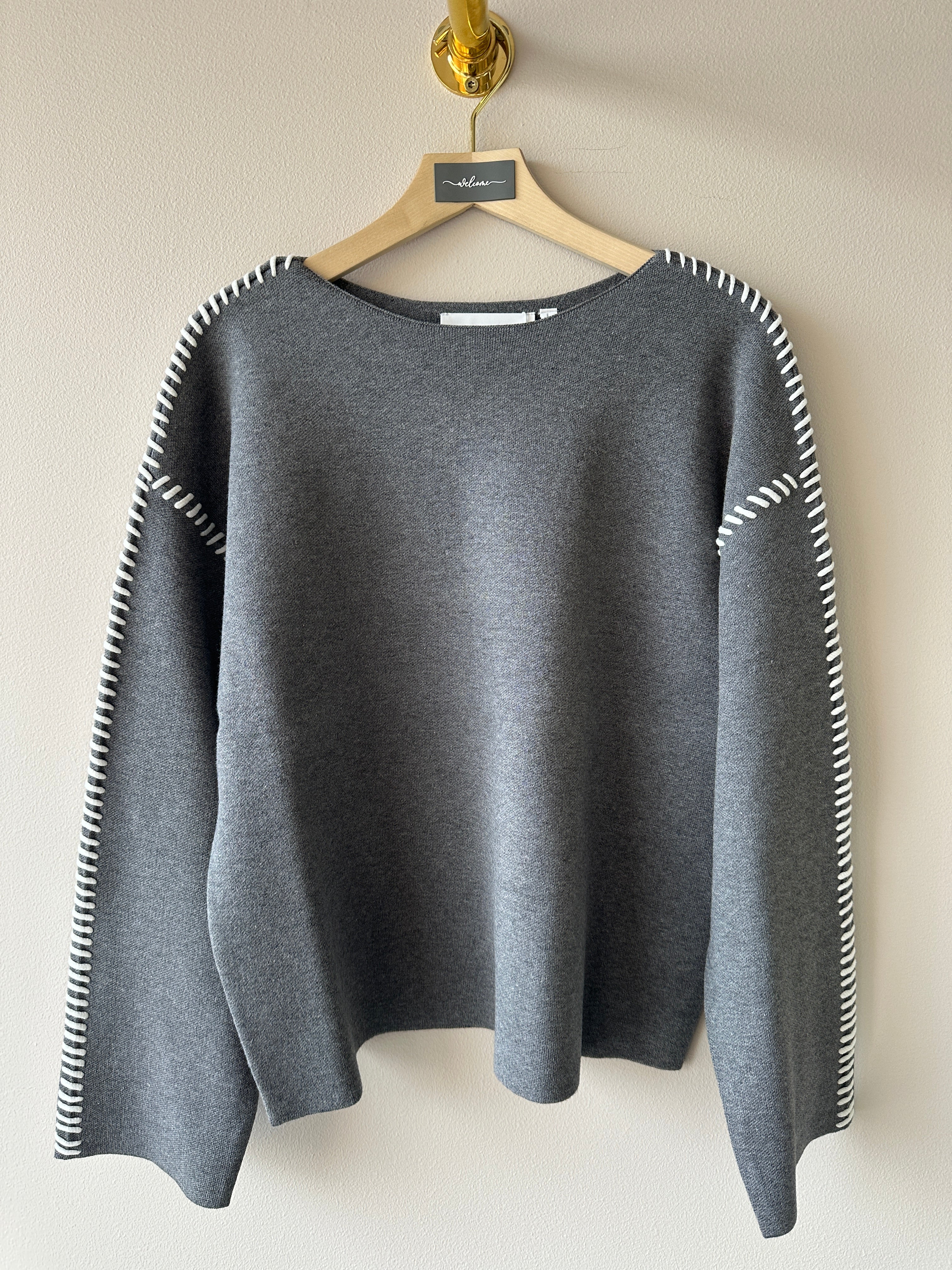 Mjuk stickad grå tröja med kontraststygn på sömmarna i vitt