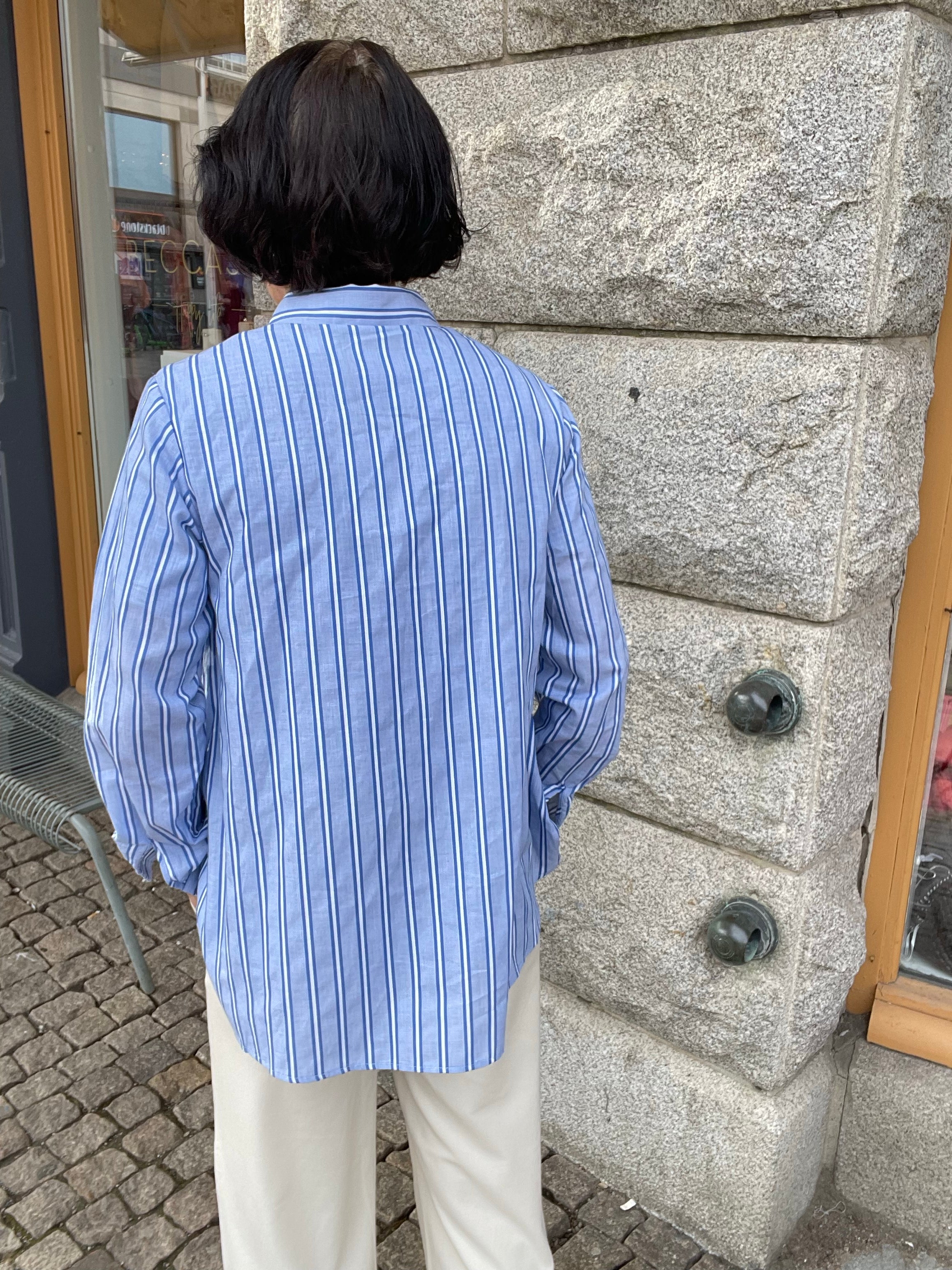 Blå vit randig skjorta med krage och dold knäppning. 