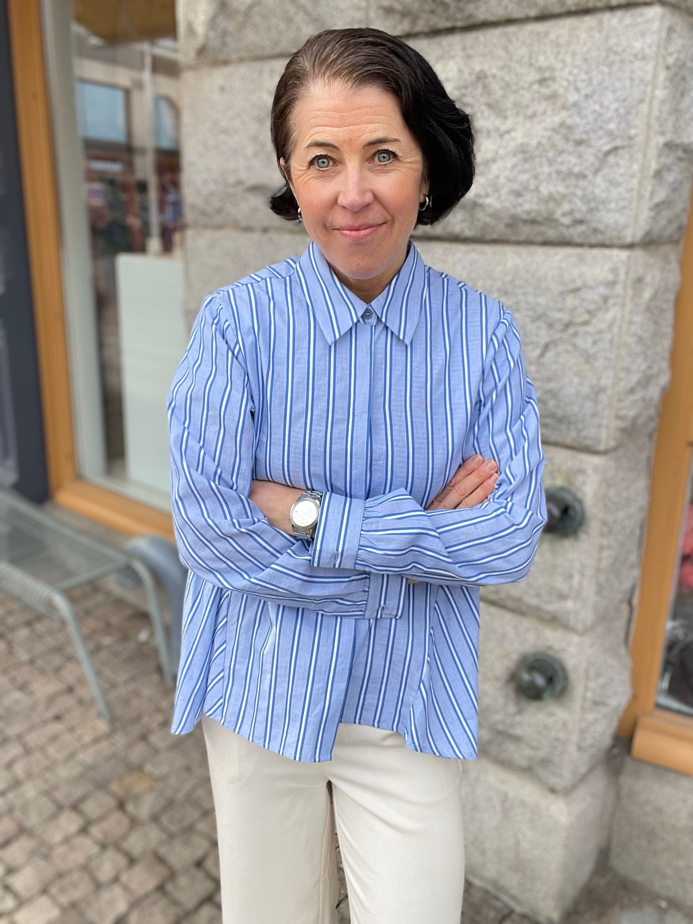 Blå vit randig skjorta med krage och dold knäppning. 