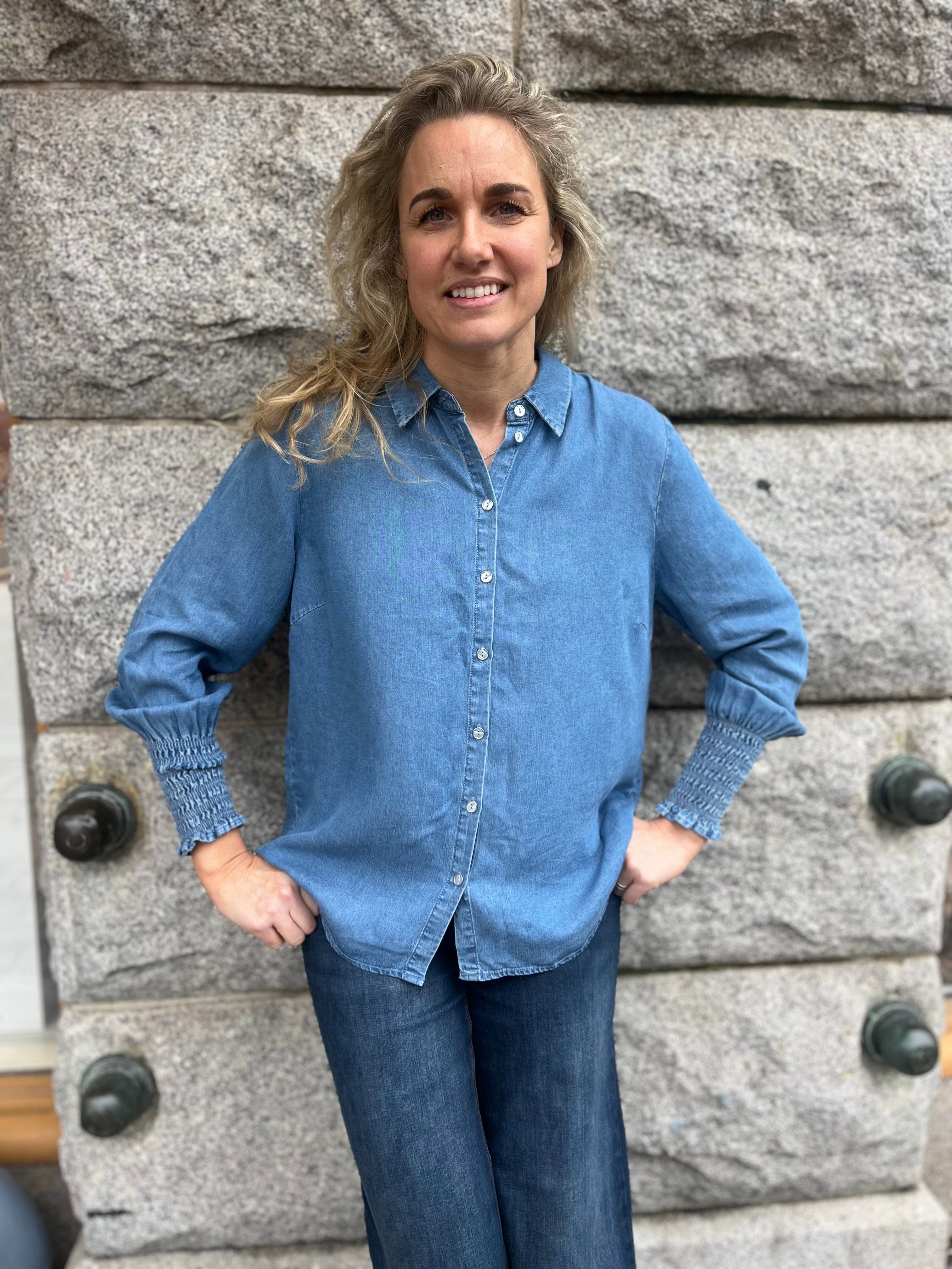 Blå jeans skjorta med resår detaljer vid ärmarna. Knäppning framtill. 