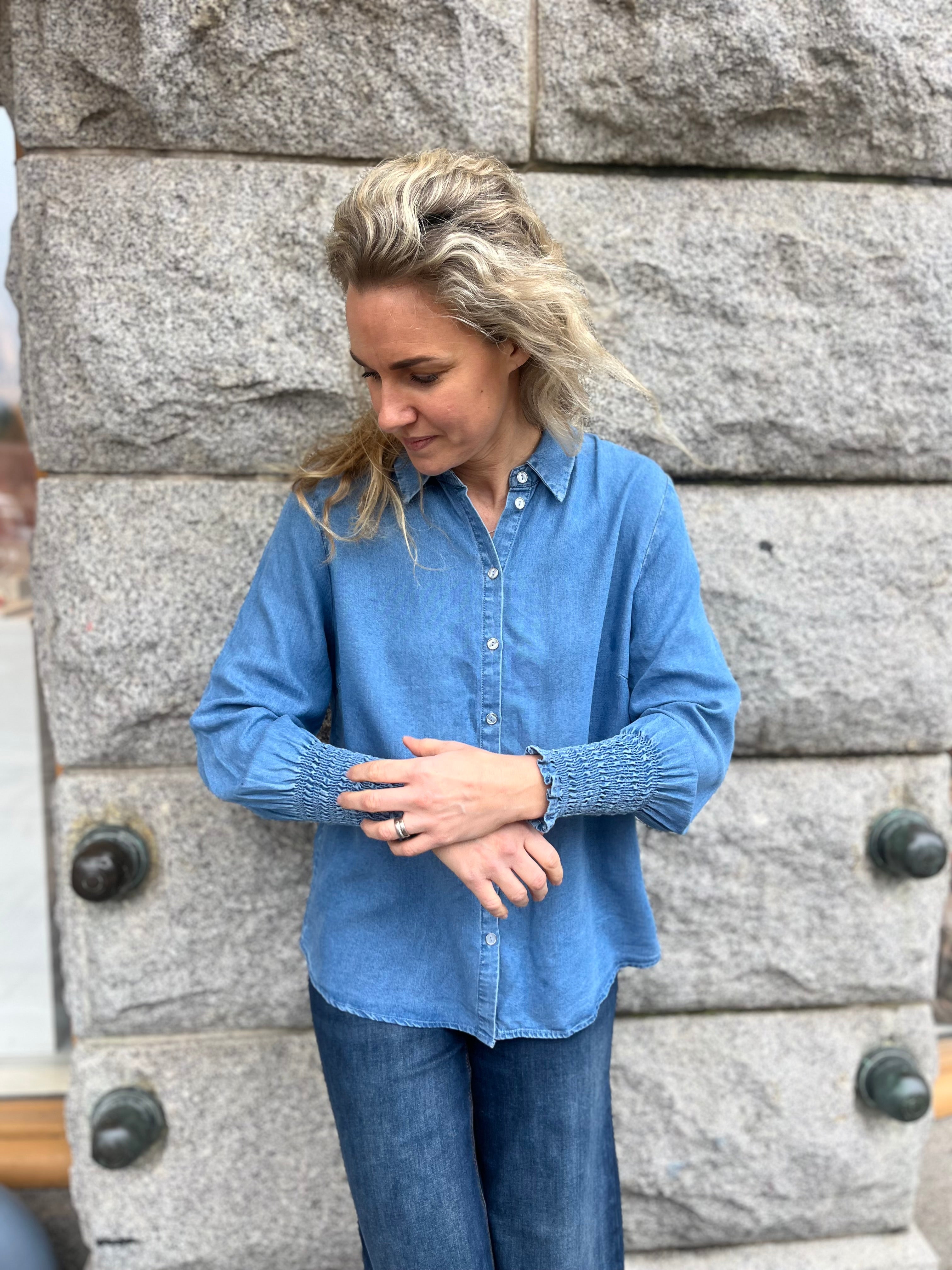 Blå jeans skjorta med resår detaljer vid ärmarna. Knäppning framtill. 