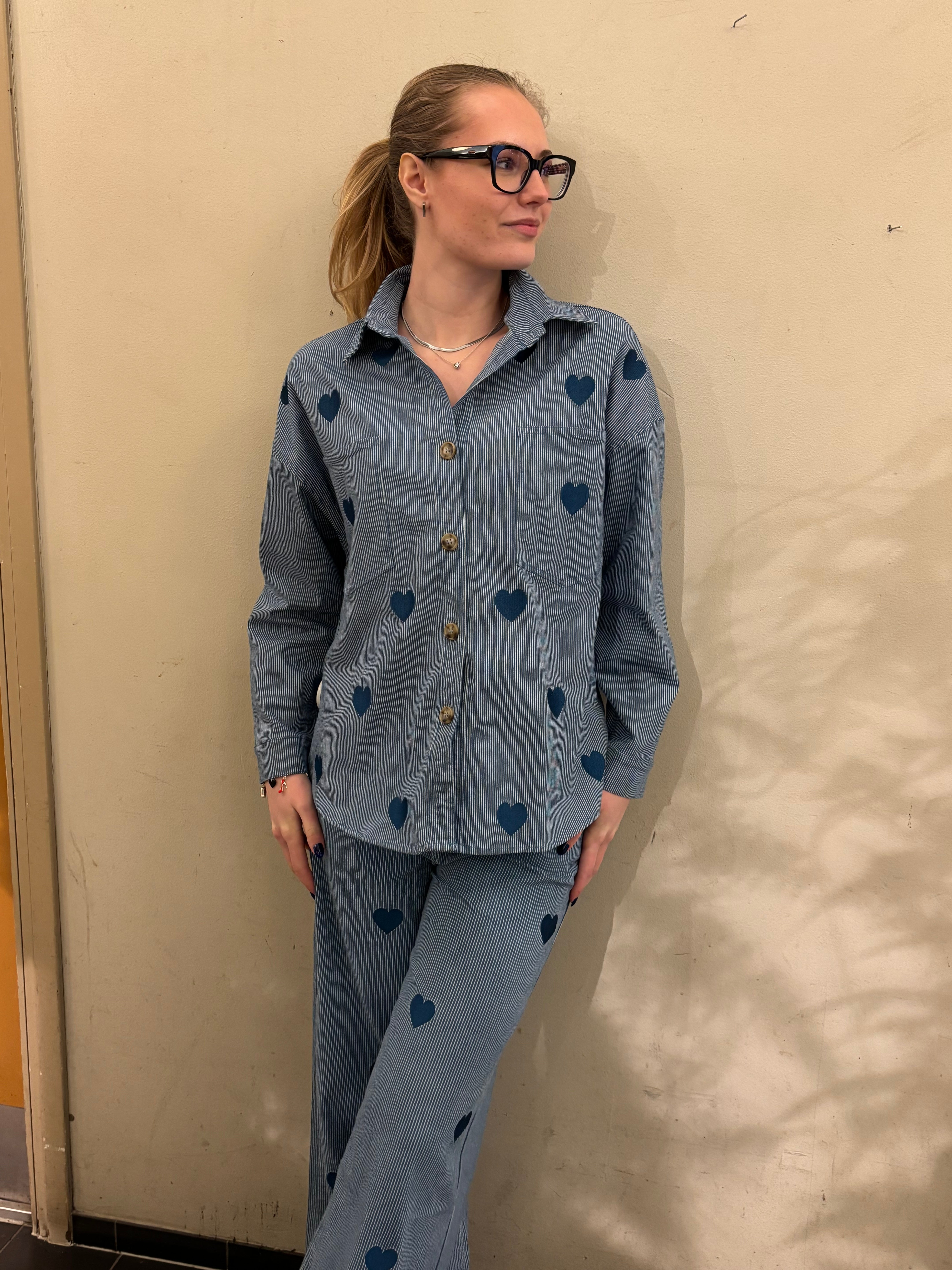 Blåvitrandig skjortjacka med broderade hjärtan, helbild framifrån stylade med matchande jeans, modell lutar mot vägg.