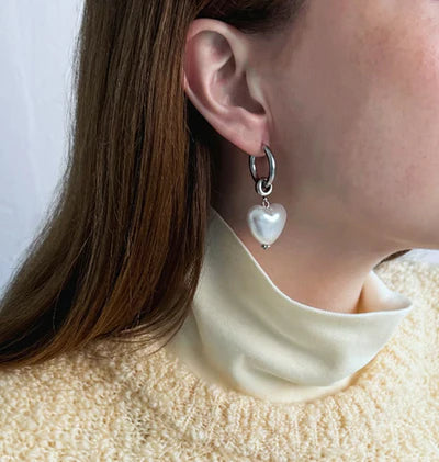I Heart You Earrings Pearl Silver - BECCASIN STORE - Silver hoop örhänge with dangling white heart-shaped pearl smycke on ear.