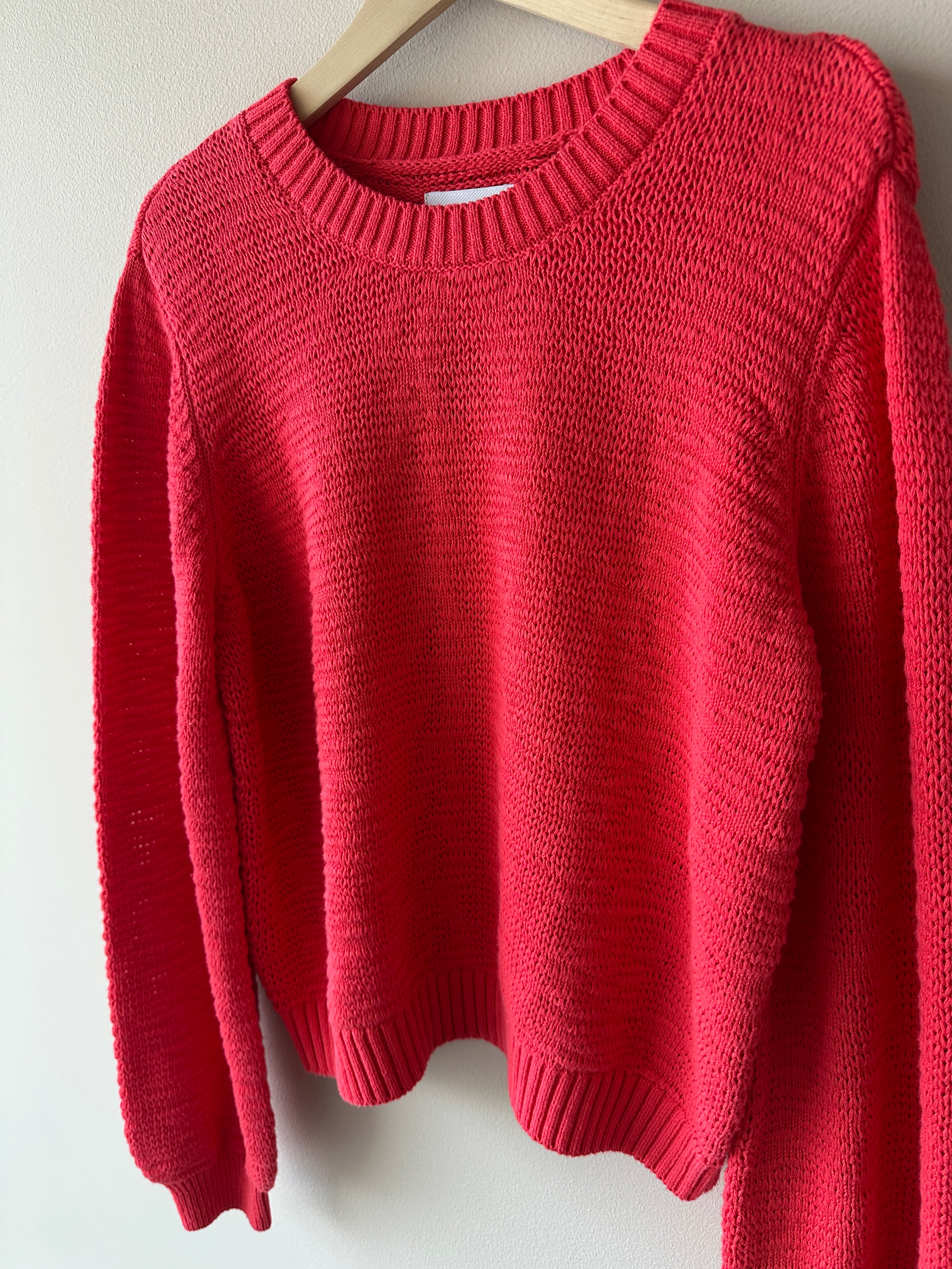 Röd sticka tröja med rund halsrigning.