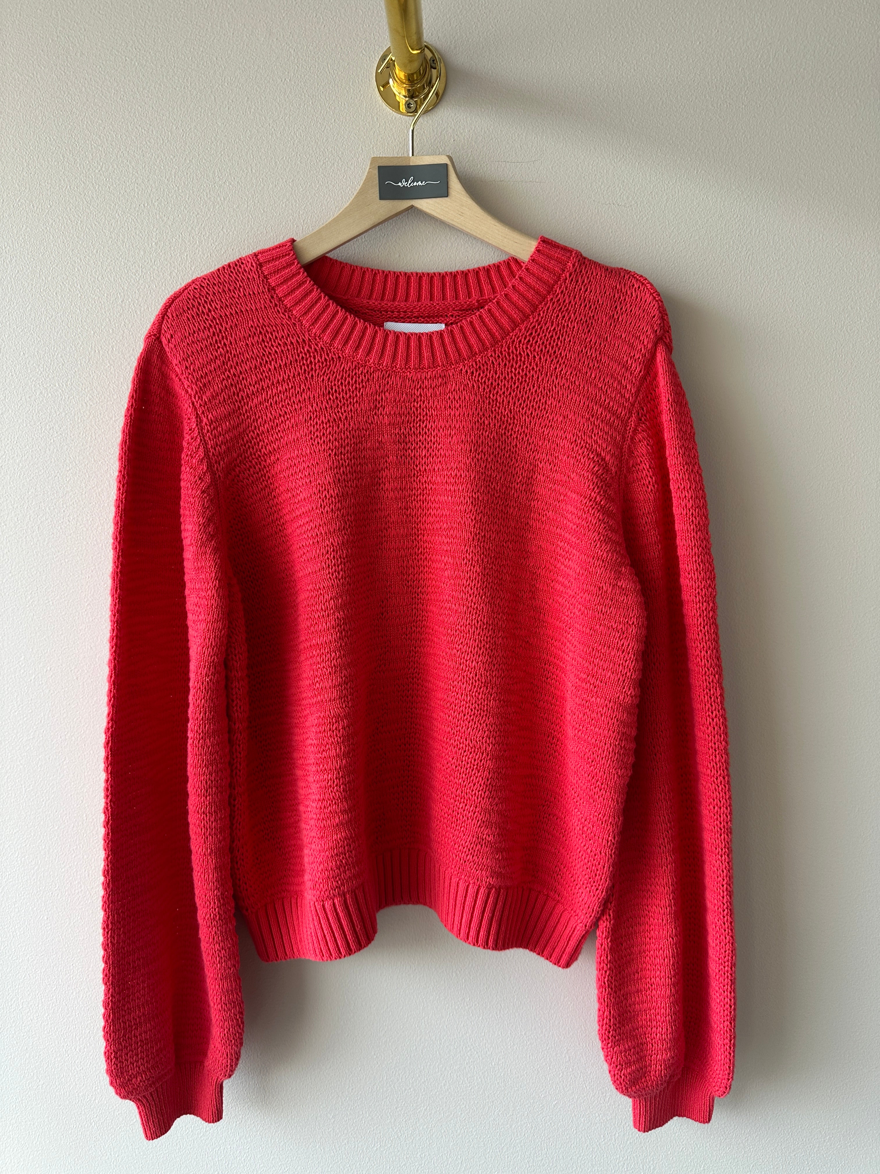 Röd sticka tröja med rund halsrigning.