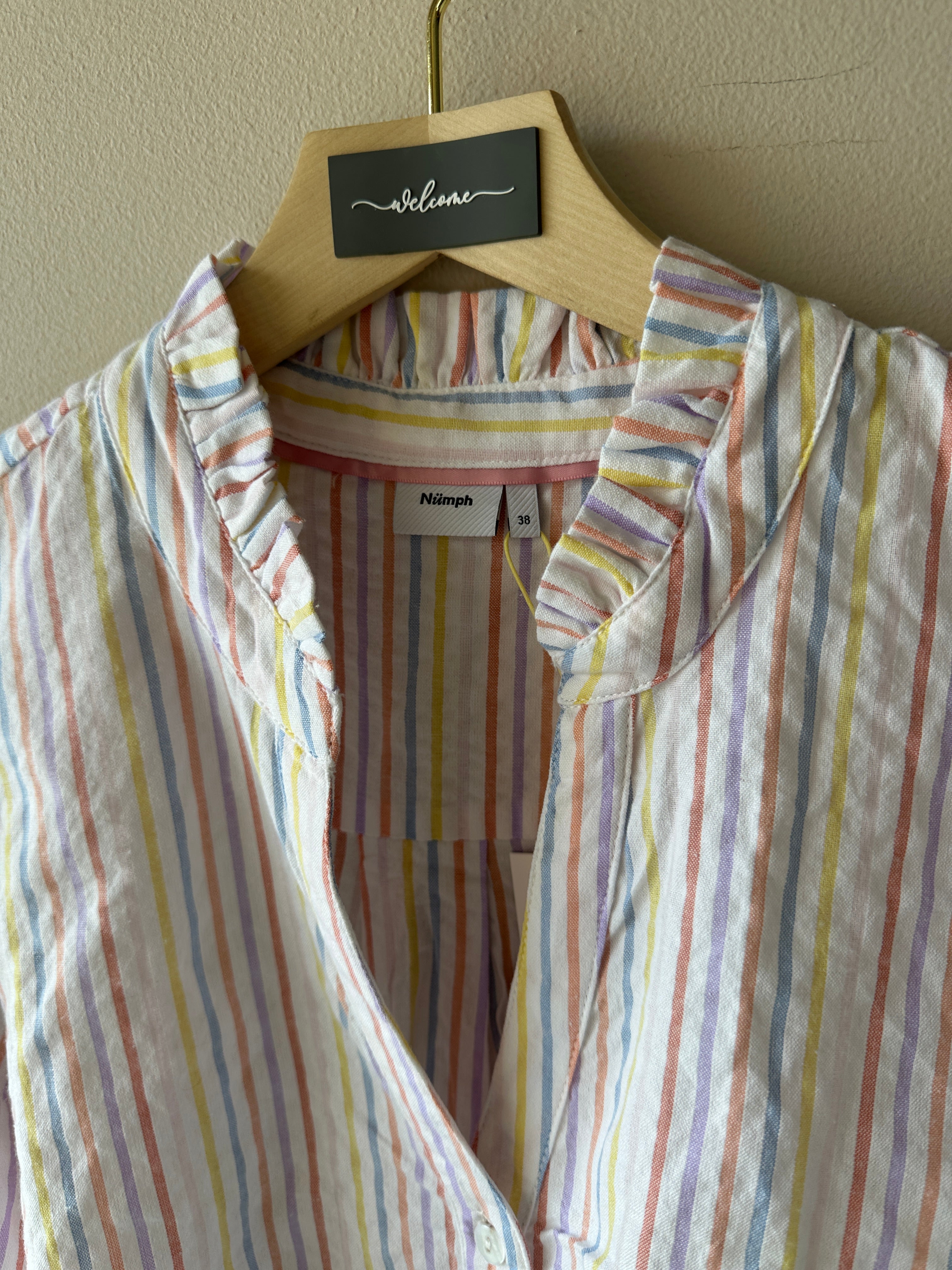 Blus med ränder i flertalet färger och dekorations kros på kragen.