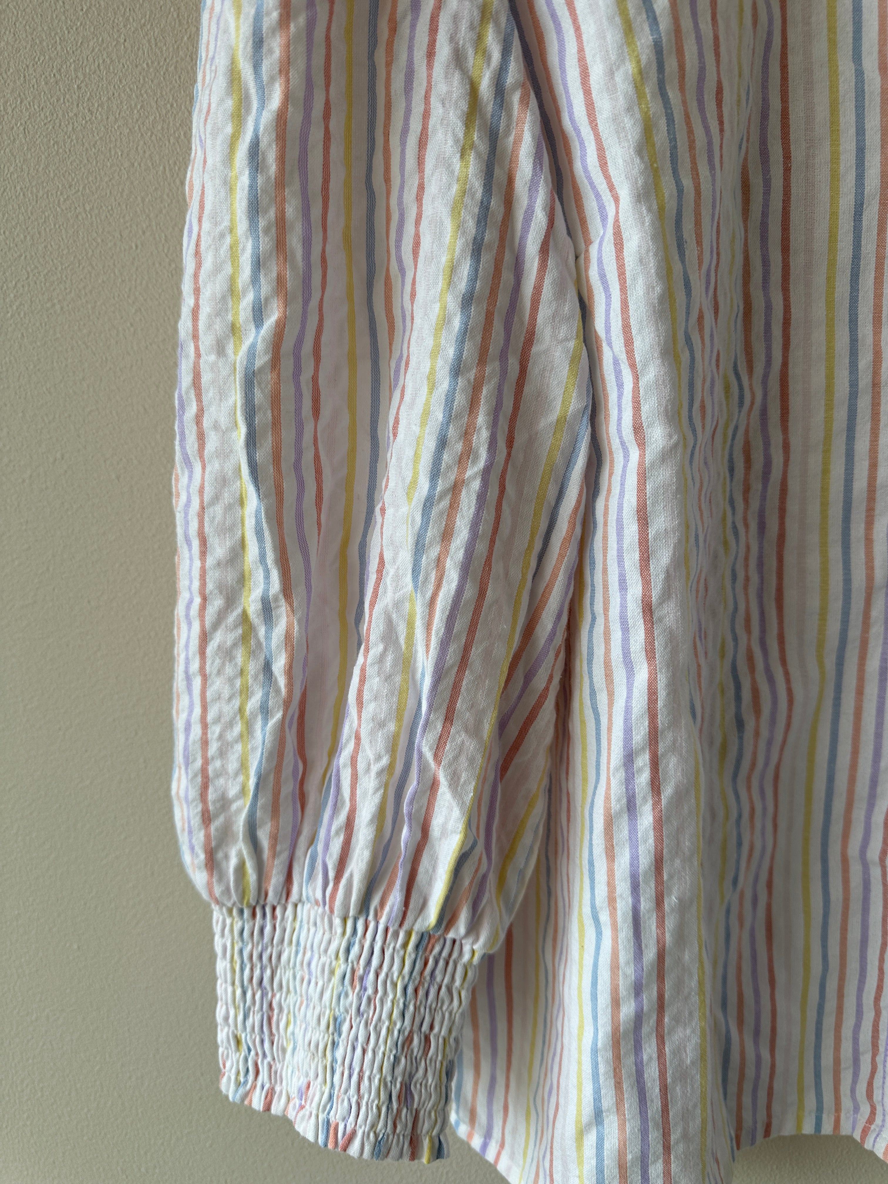 Blus med ränder i flertalet färger och dekorations kros på kragen.