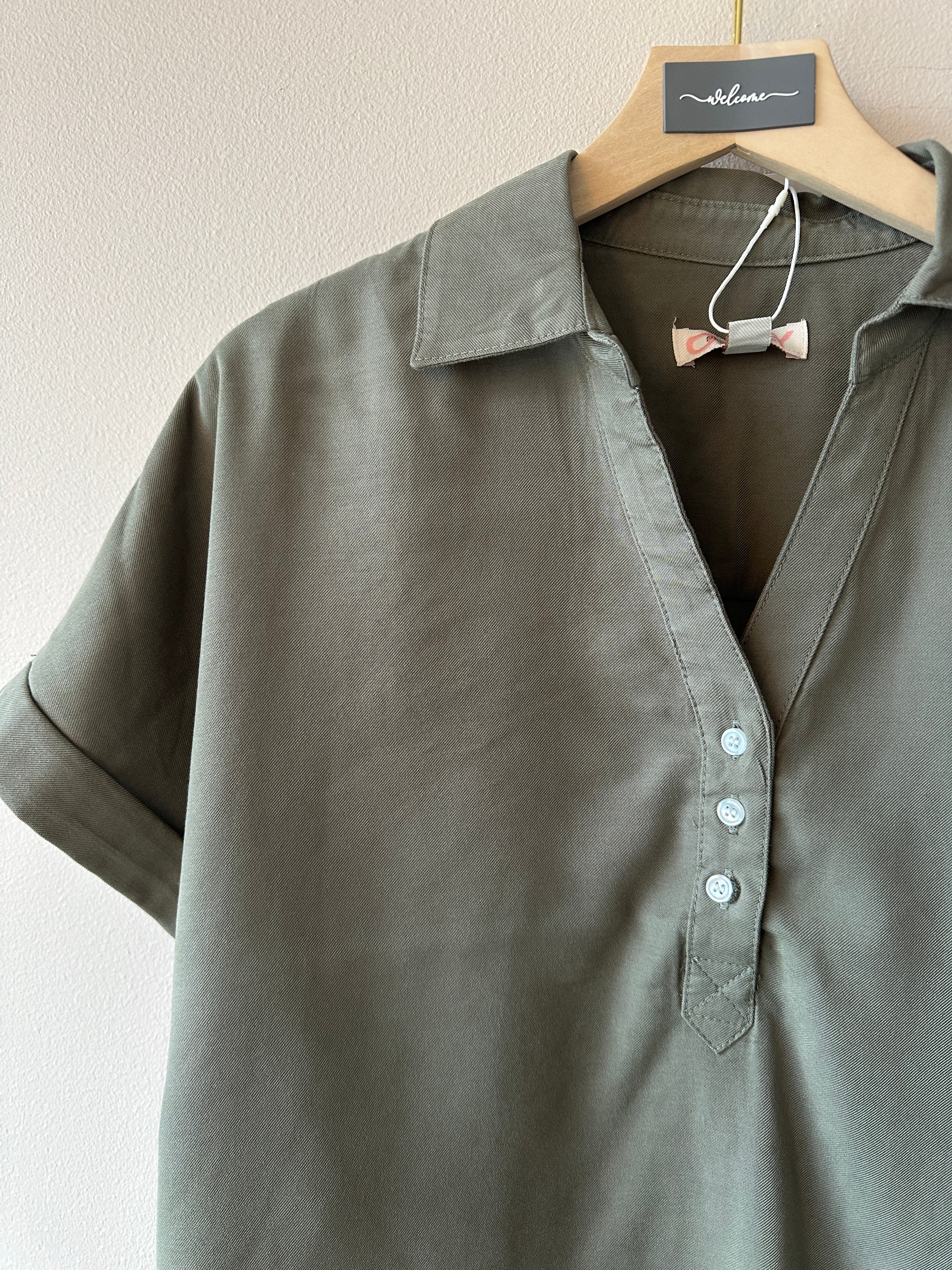 Oliv grön piké med korta ärmar och treknappar i v-ringningen. 