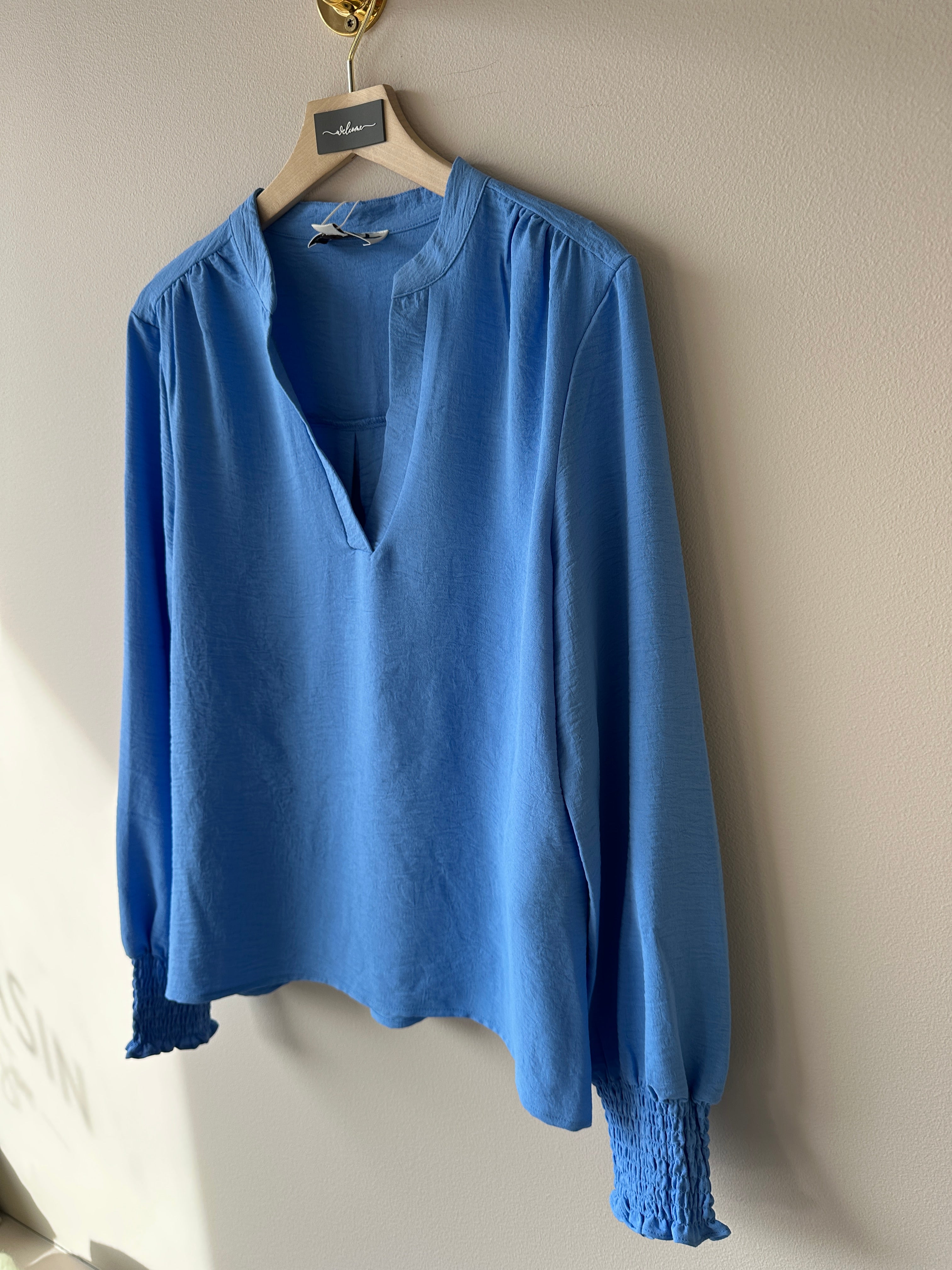 Blå v-ringad blus med långa ärmar. 