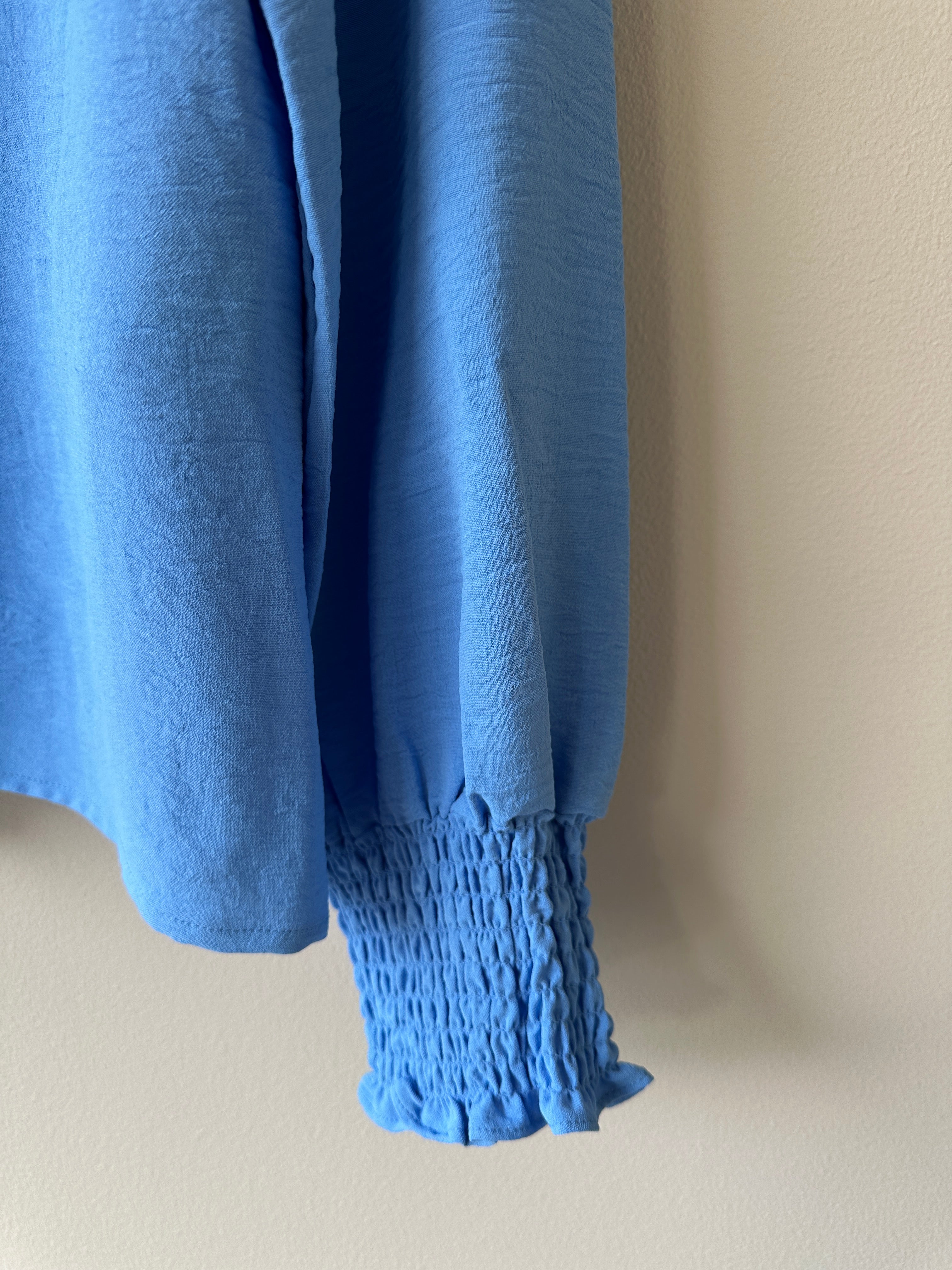 Blå v-ringad blus med långa ärmar. 