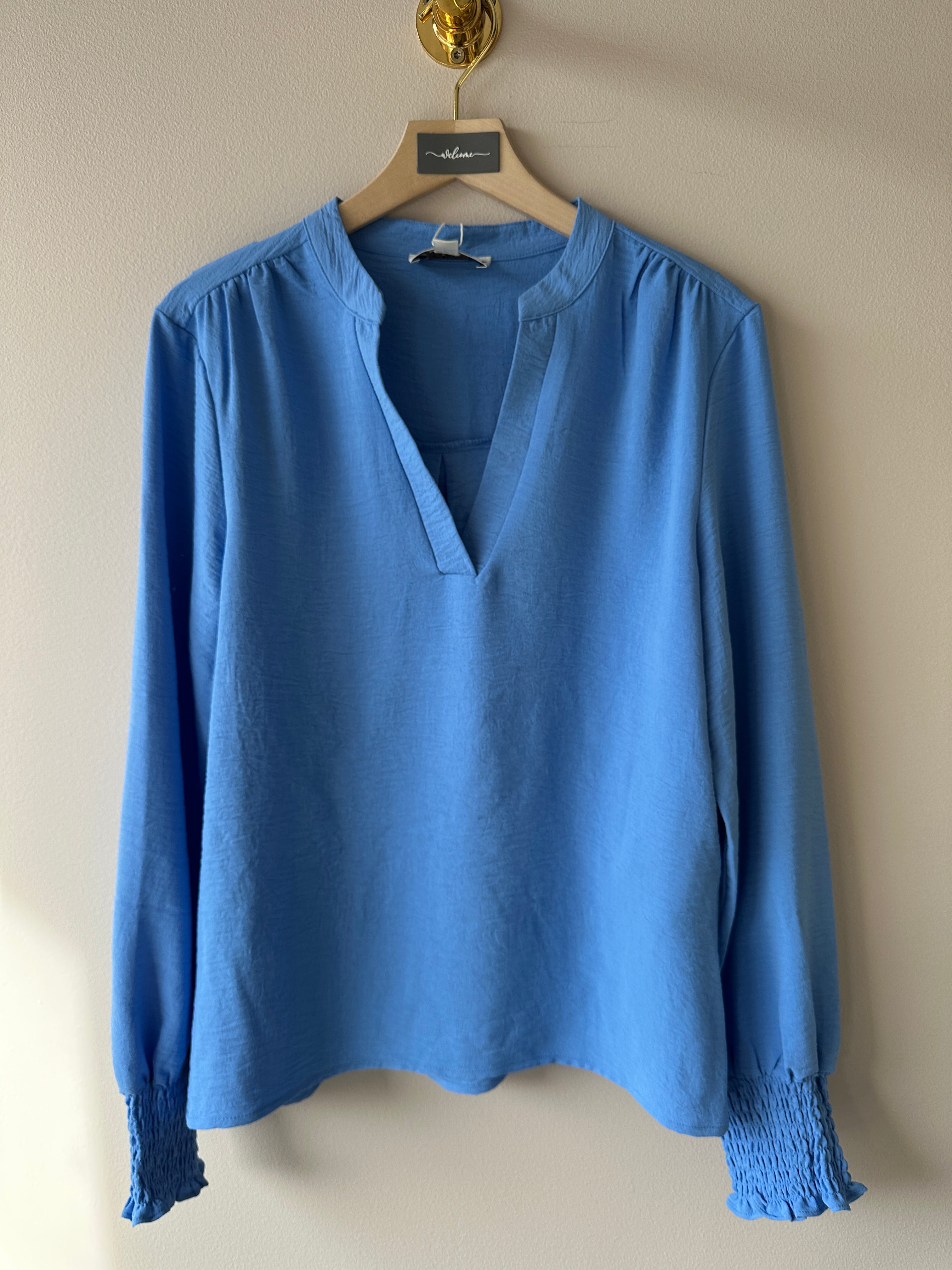 Blå v-ringad blus med långa ärmar. 