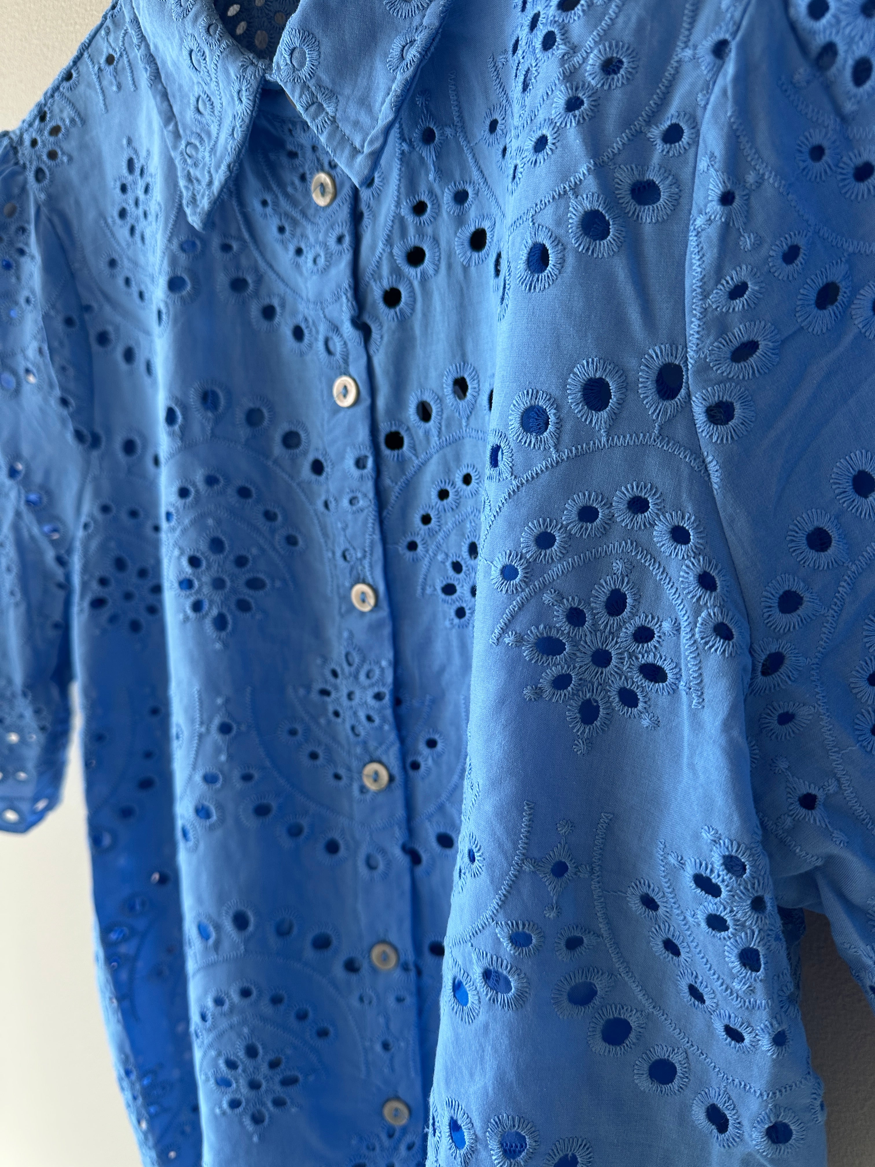 Blå skjorta med dekoration av broderi men knäppning framtill. 