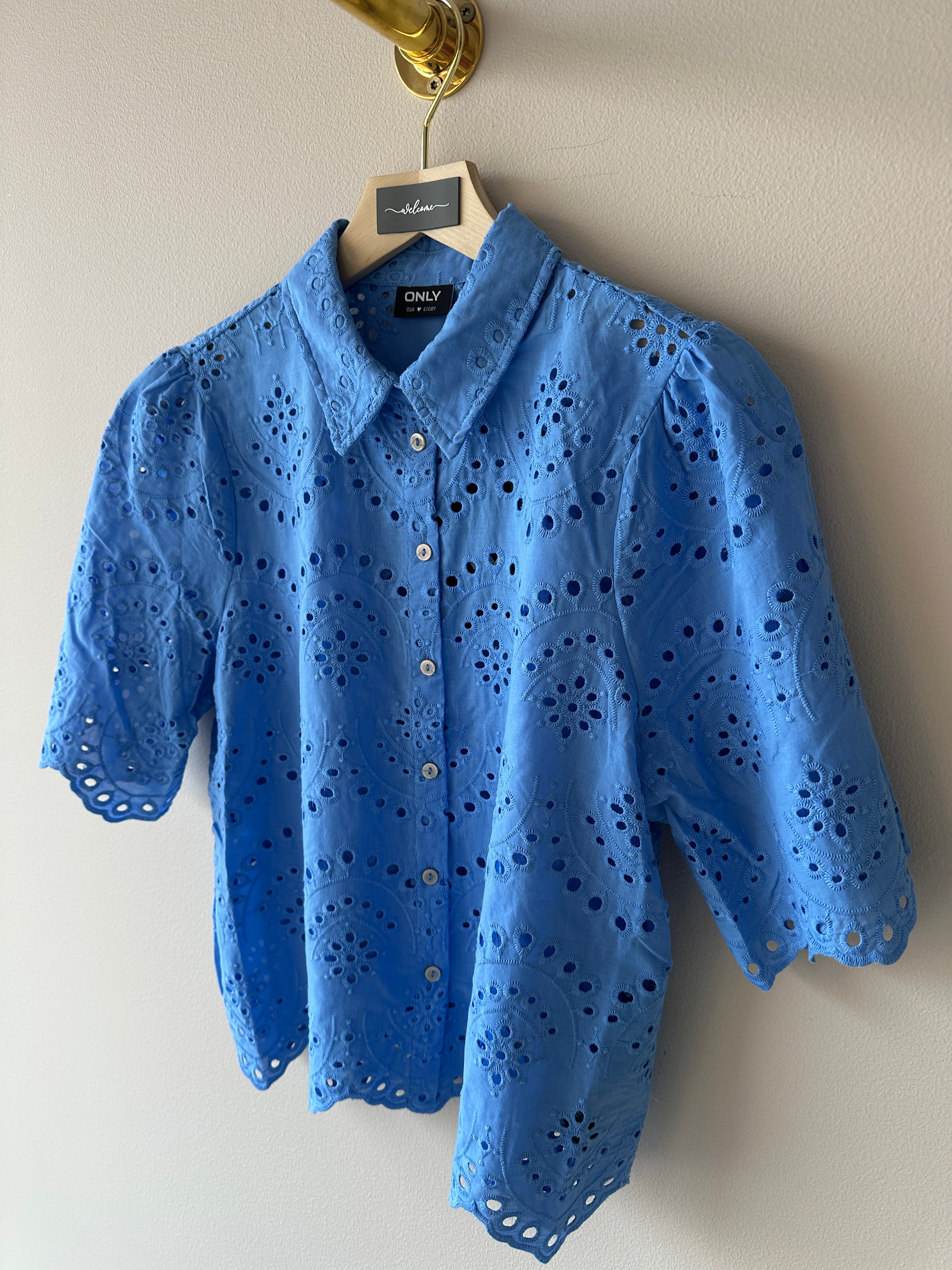 Blå skjorta med dekoration av broderi men knäppning framtill. 