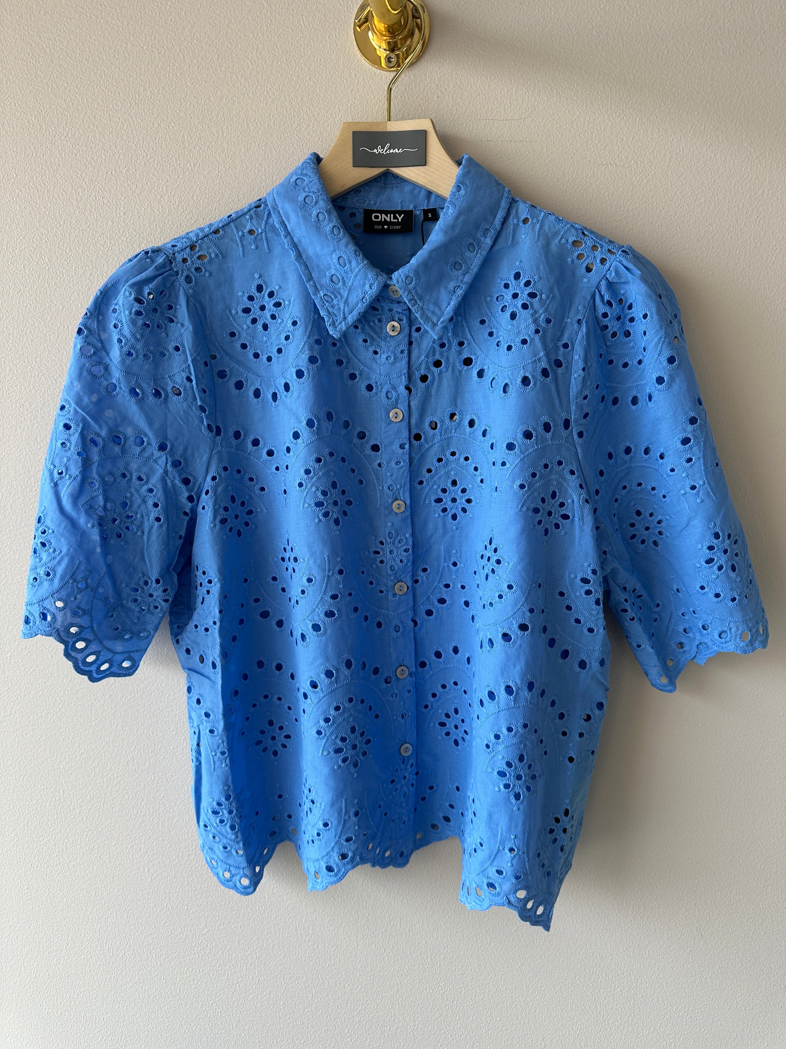 Blå skjorta med dekoration av broderi men knäppning framtill. 