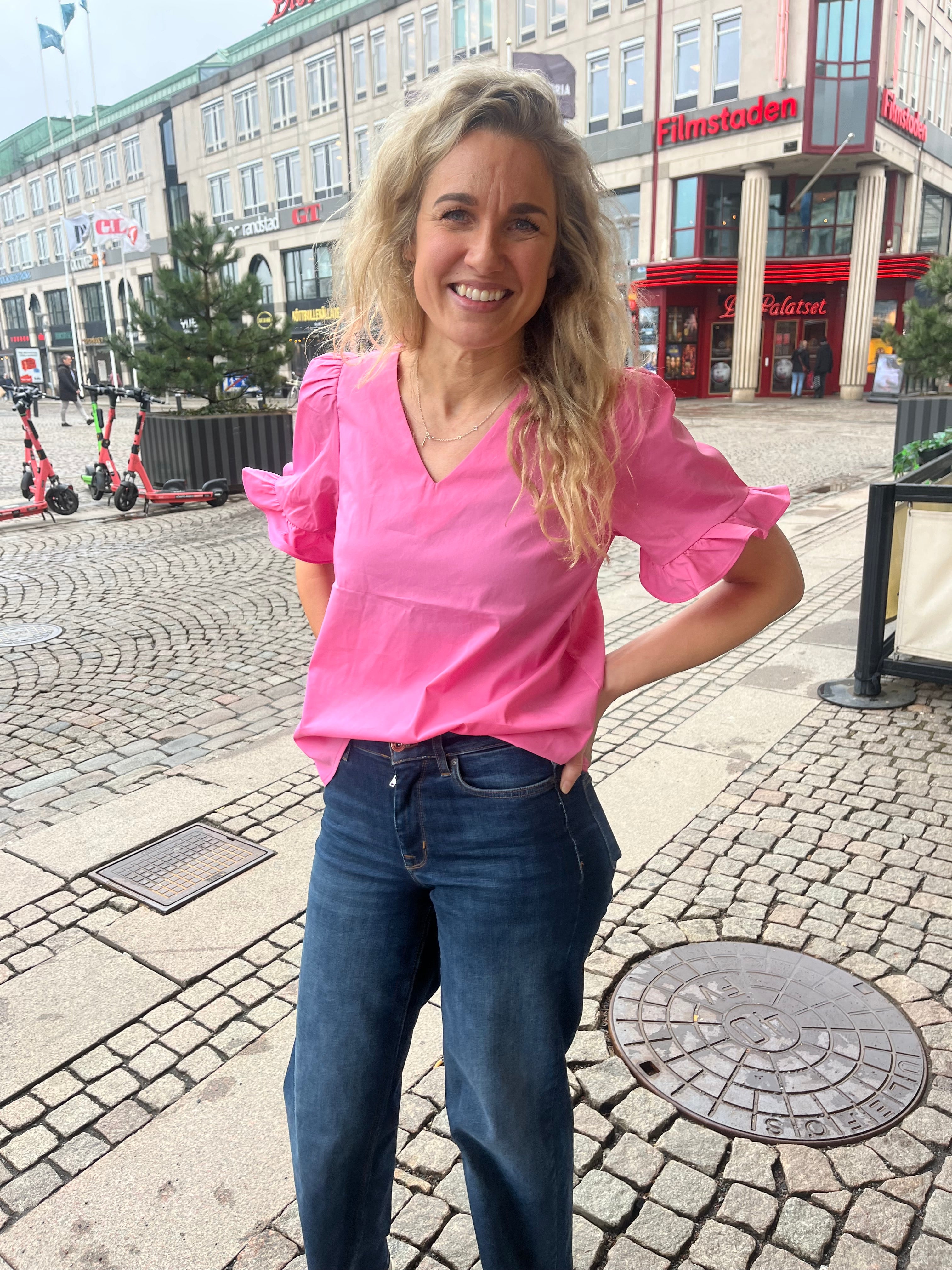 Rosa blus med volanger och v-ringning. 