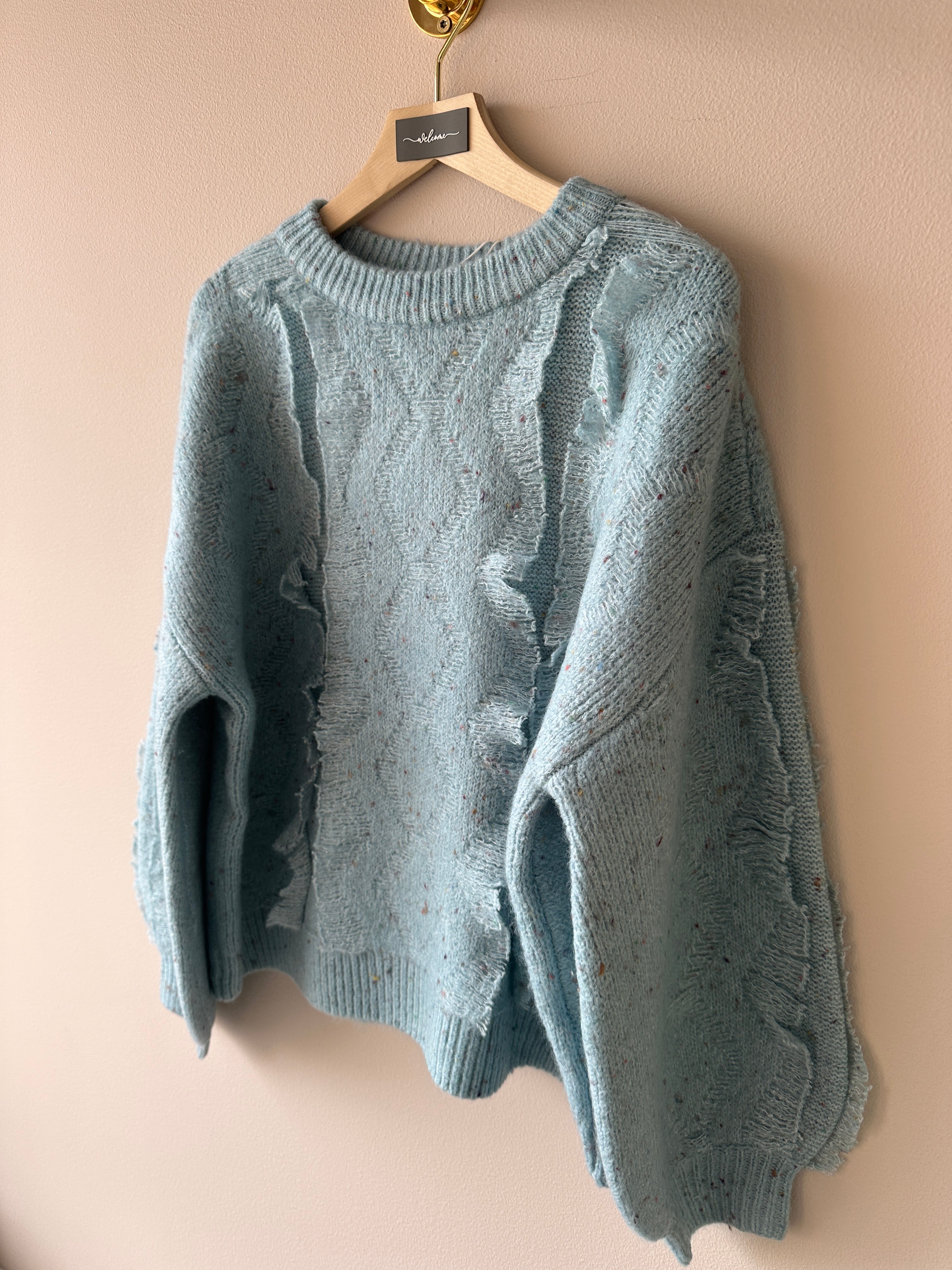 Stickad tröja en en blå grå färg. Långa ärmar och detaljer framtill. 