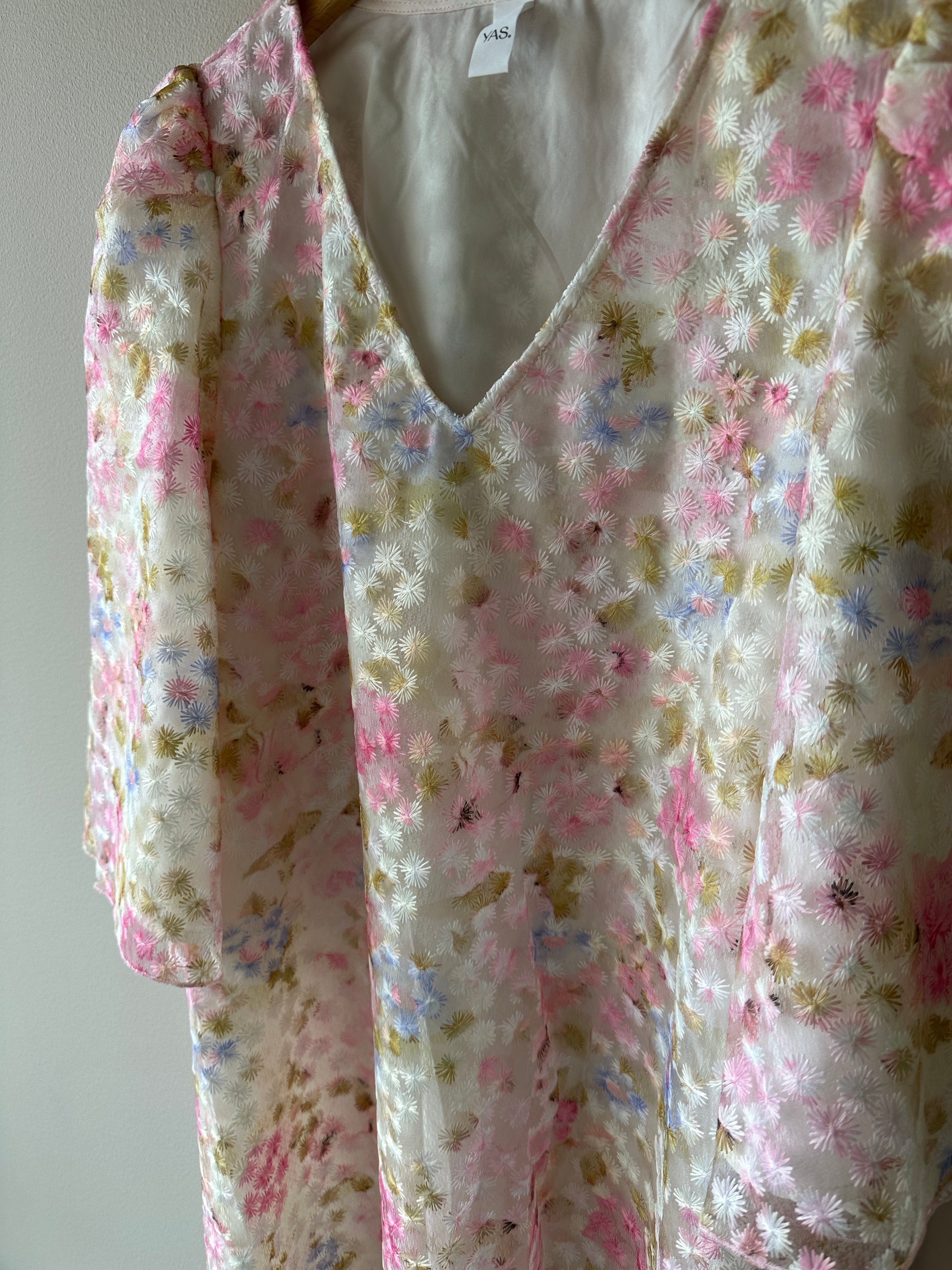 Vit klänning med blommor i rosa,vit, grön och blå. Rak passform med 3/4 ärmar. 