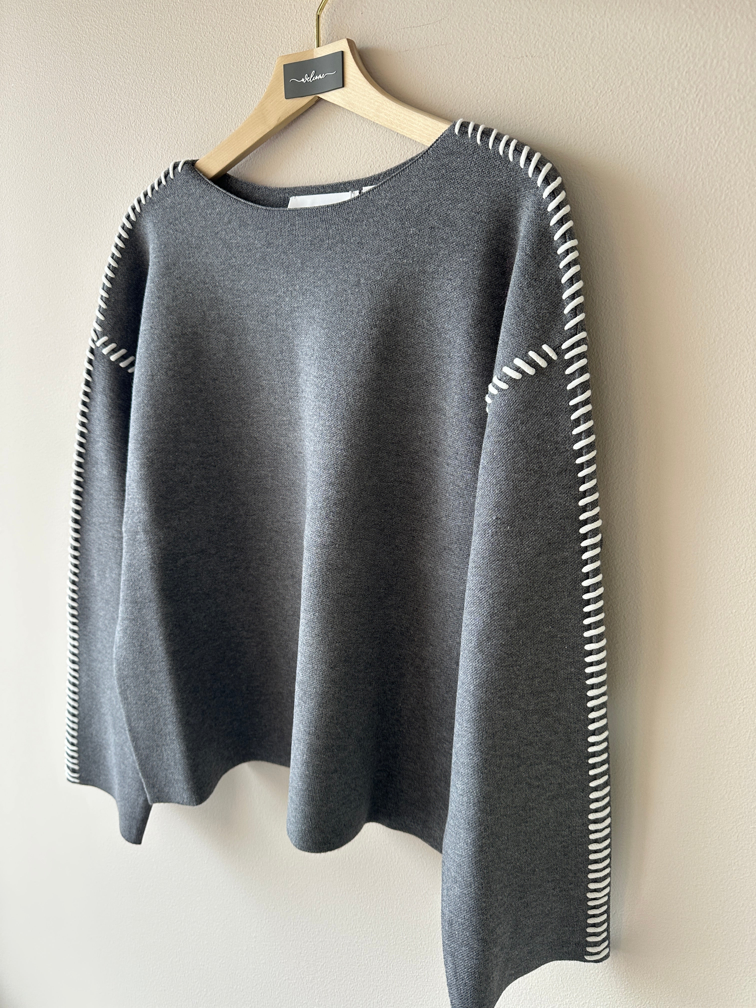 Mjuk stickad grå tröja med kontraststygn på sömmarna i vitt